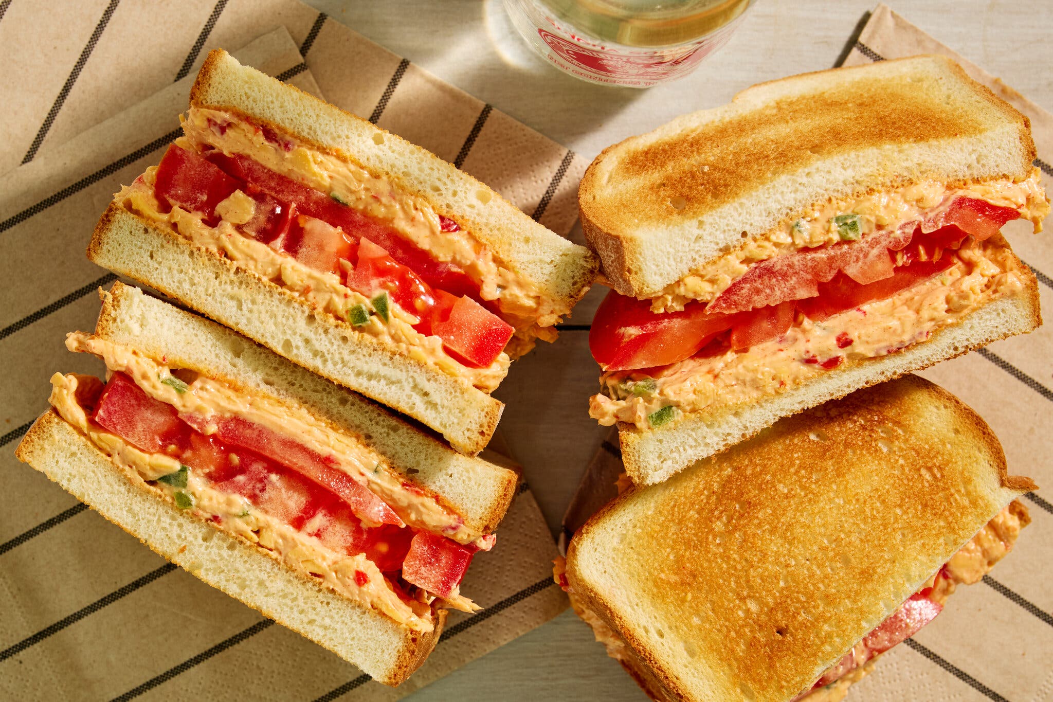 A side image of halved pimento cheese and tomato sandwiches.