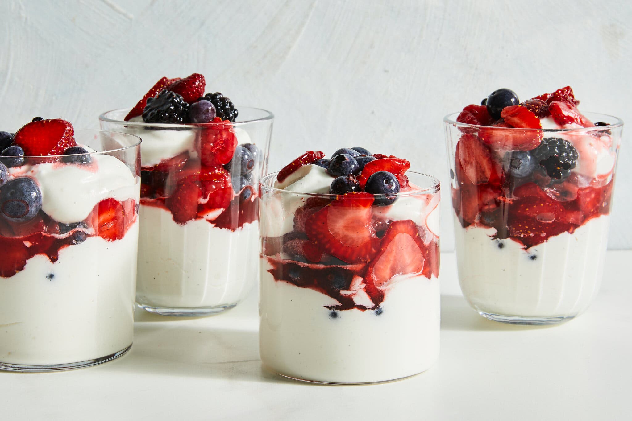 A side image of four cups filled with whipped cream and topped with berries.