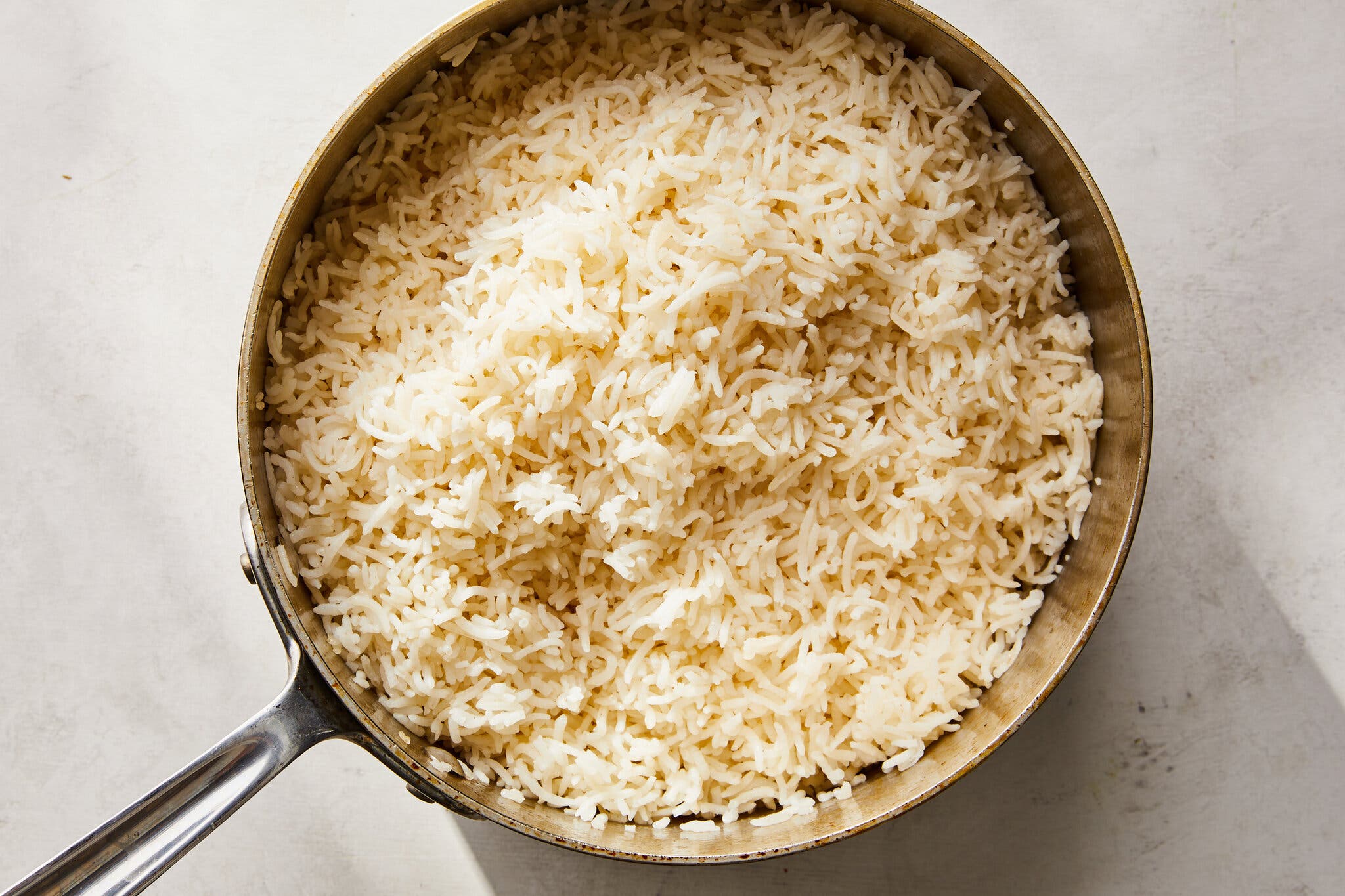 An overhead shot shows a pot of white long-grain rice.