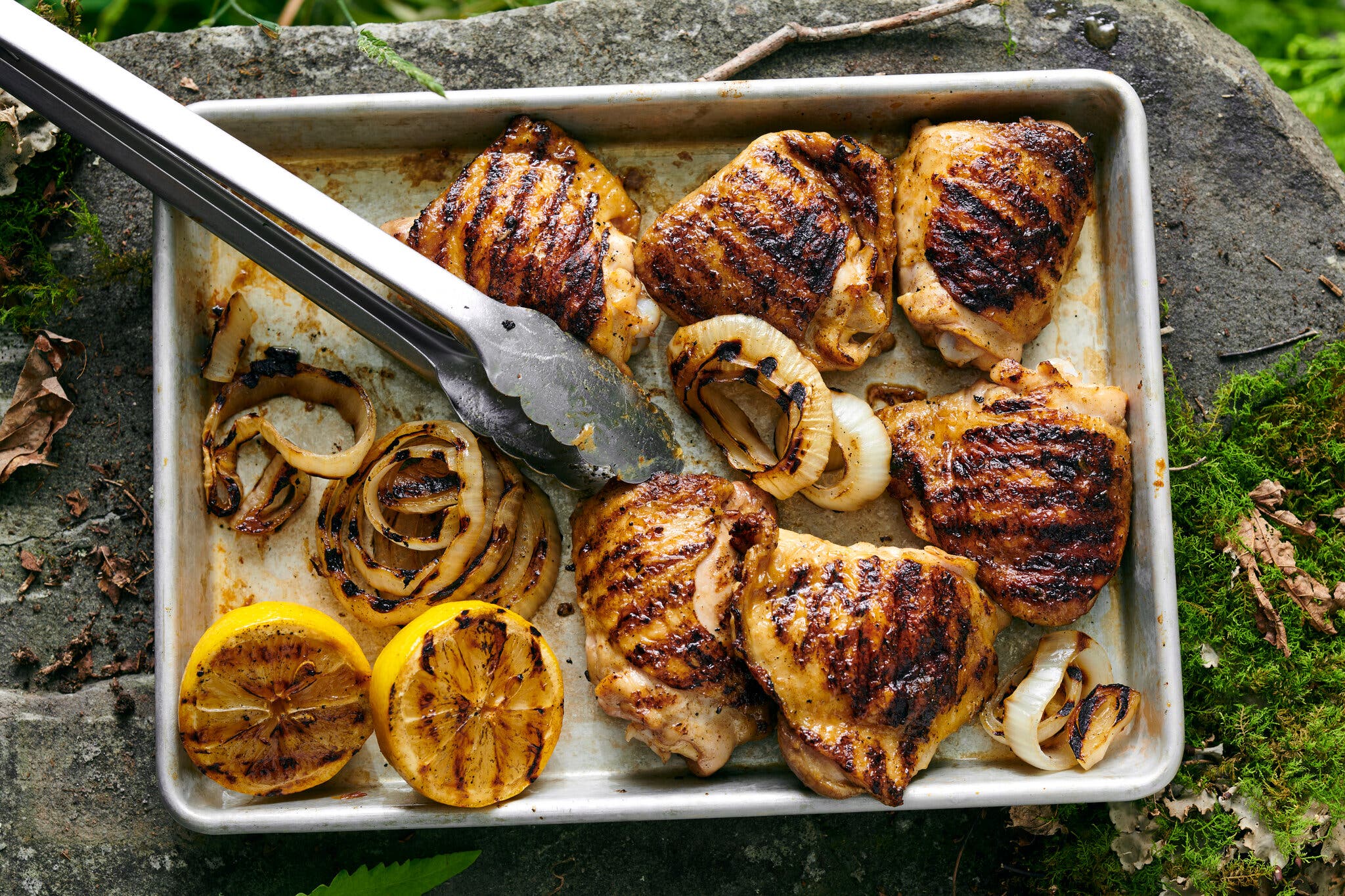 An overhead image of grilled chicken thighs on a sheet pan.