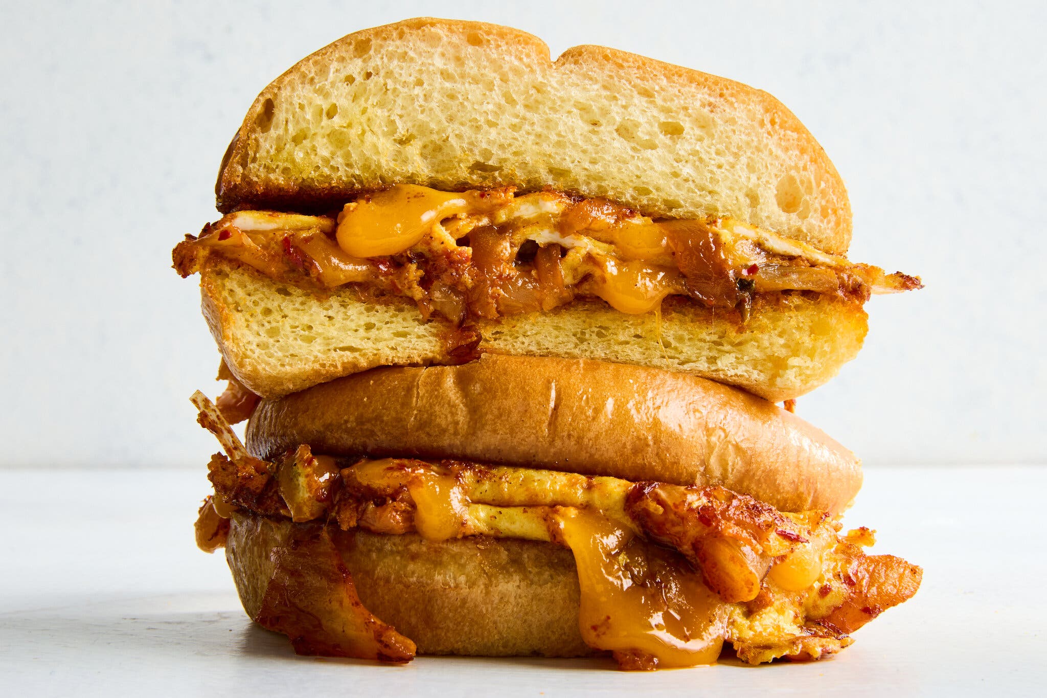 A cross-section of a kimchi, egg and cheese sandwich, with melted cheese oozing