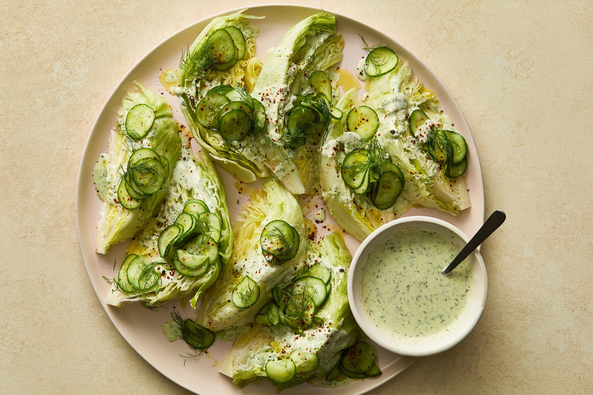 An overhead image of a platter topped with wedges, slivered cucumbers and dill.