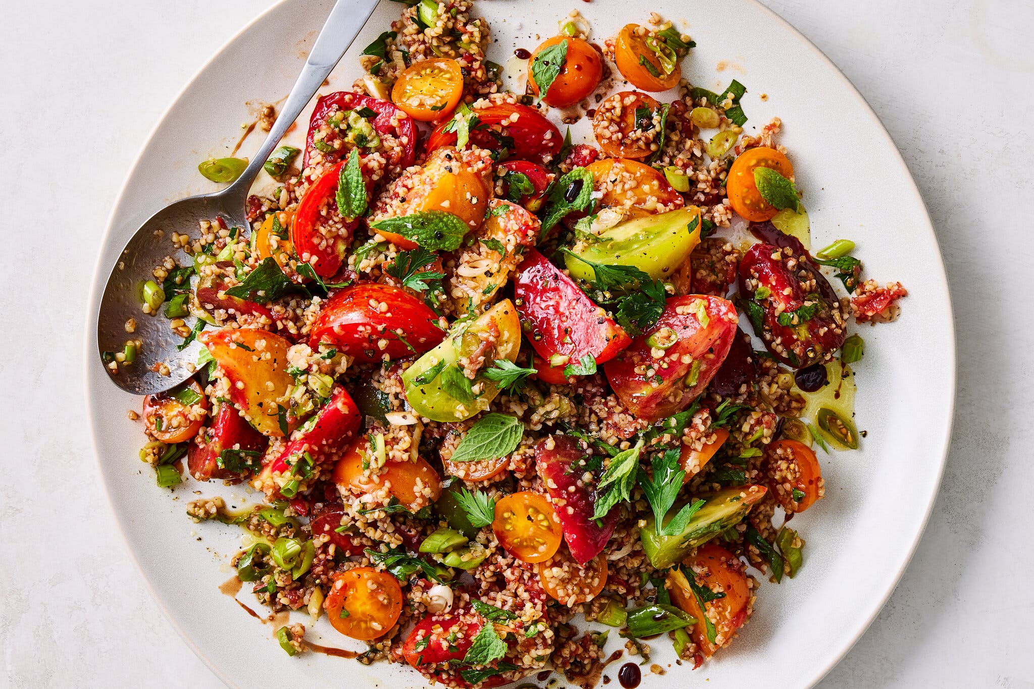 A plate of bulgar salad with heirloom and cherry tomatoes and fresh herbs.  