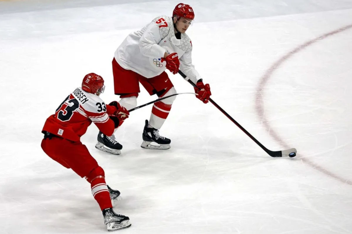 Feb 11, 2022; Beijing, China; ROC defender Alexander Nikishin (57) passes the puck against Denmark forward Julian Jakobsen (33) in men's ice hockey Group B play during the Beijing 2022 Olympic Winter Games at National Indoor Stadium. Mandatory Credit: Peter Casey-Imagn Images