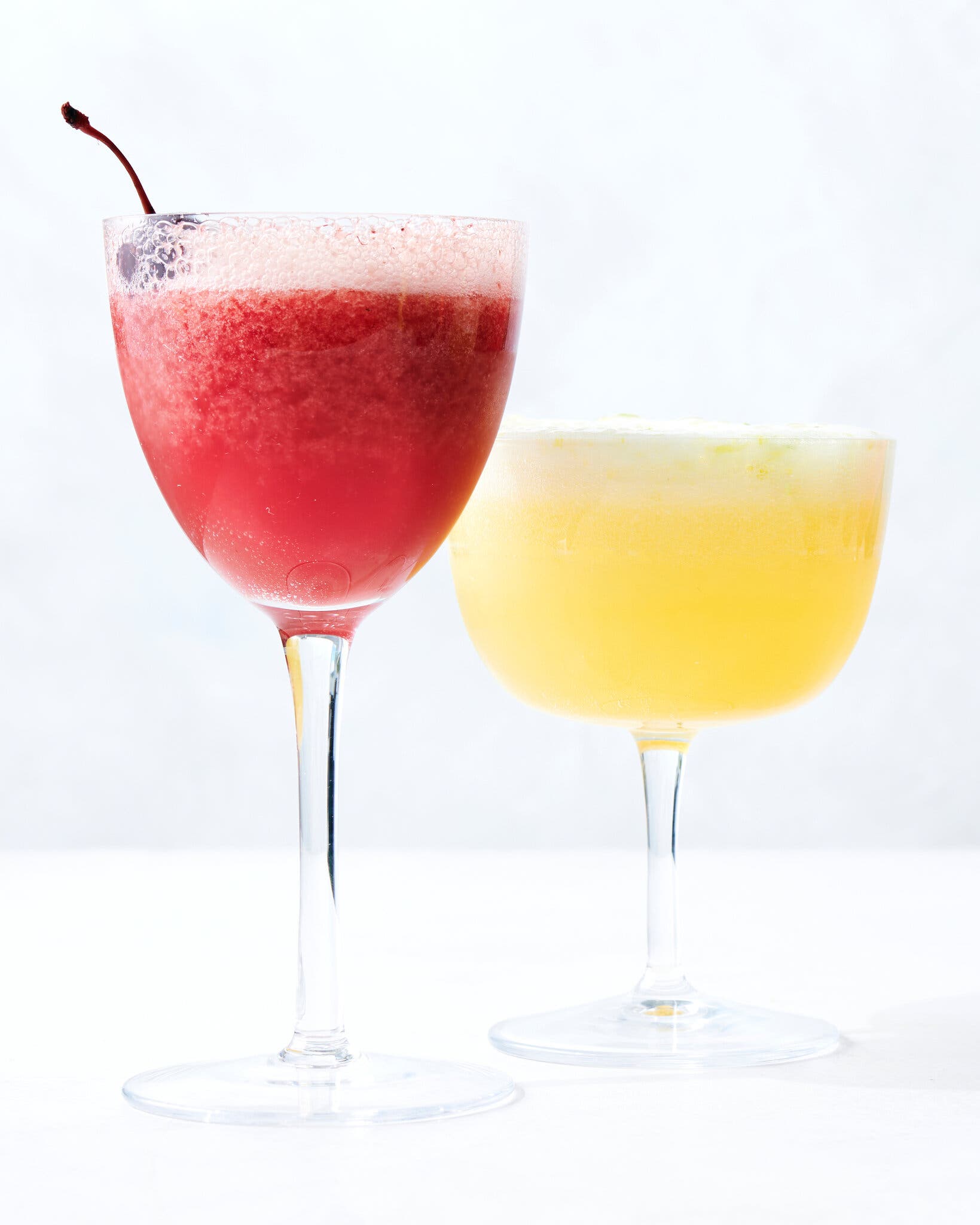 A side image of two frozen cocktails: one pink and garnished with a cocktail, and the other one yellow.