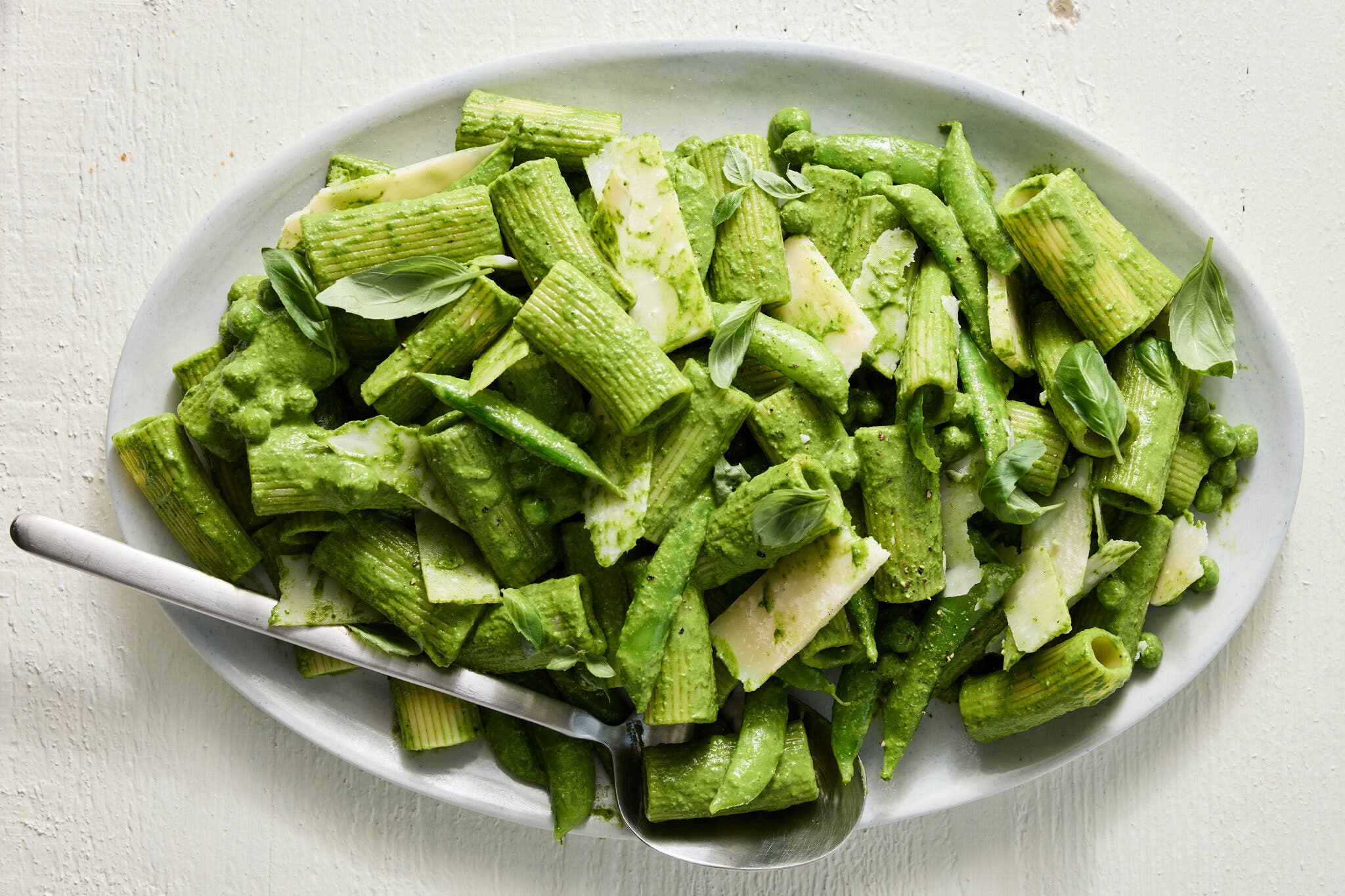 An overhead image of tube pasta tossed in a green sauce.
