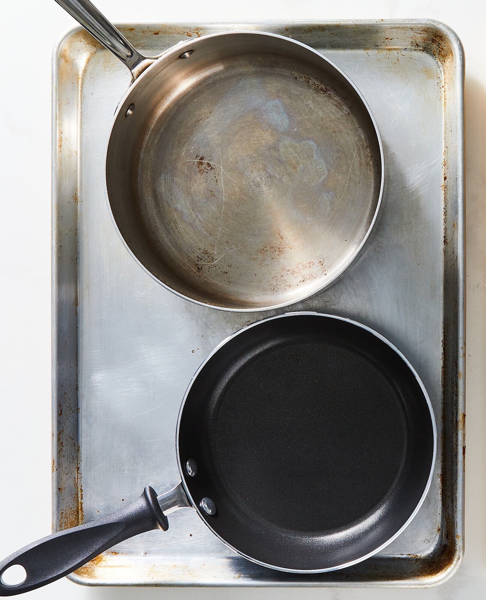 An overhead image of a rimmed sheet pan and two pans.