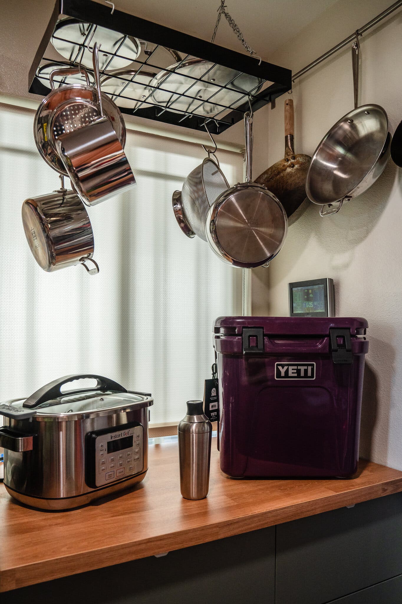 A side image of a Yeti cooler, a multi-cooker and a cocktail shaker on a counter.