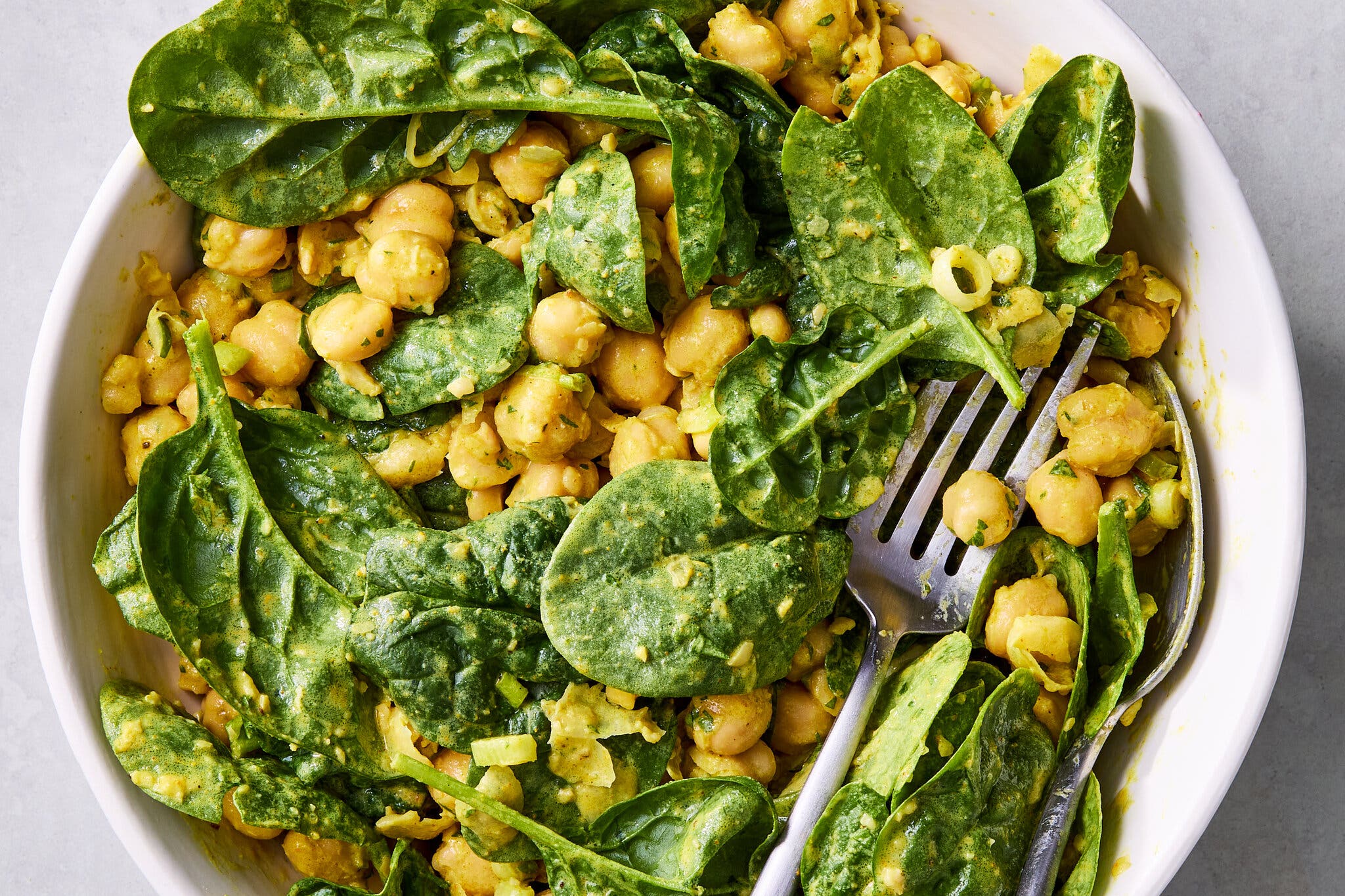 An overhead image of a bowl of chickpea spinach salad with curry yogurt dressing.