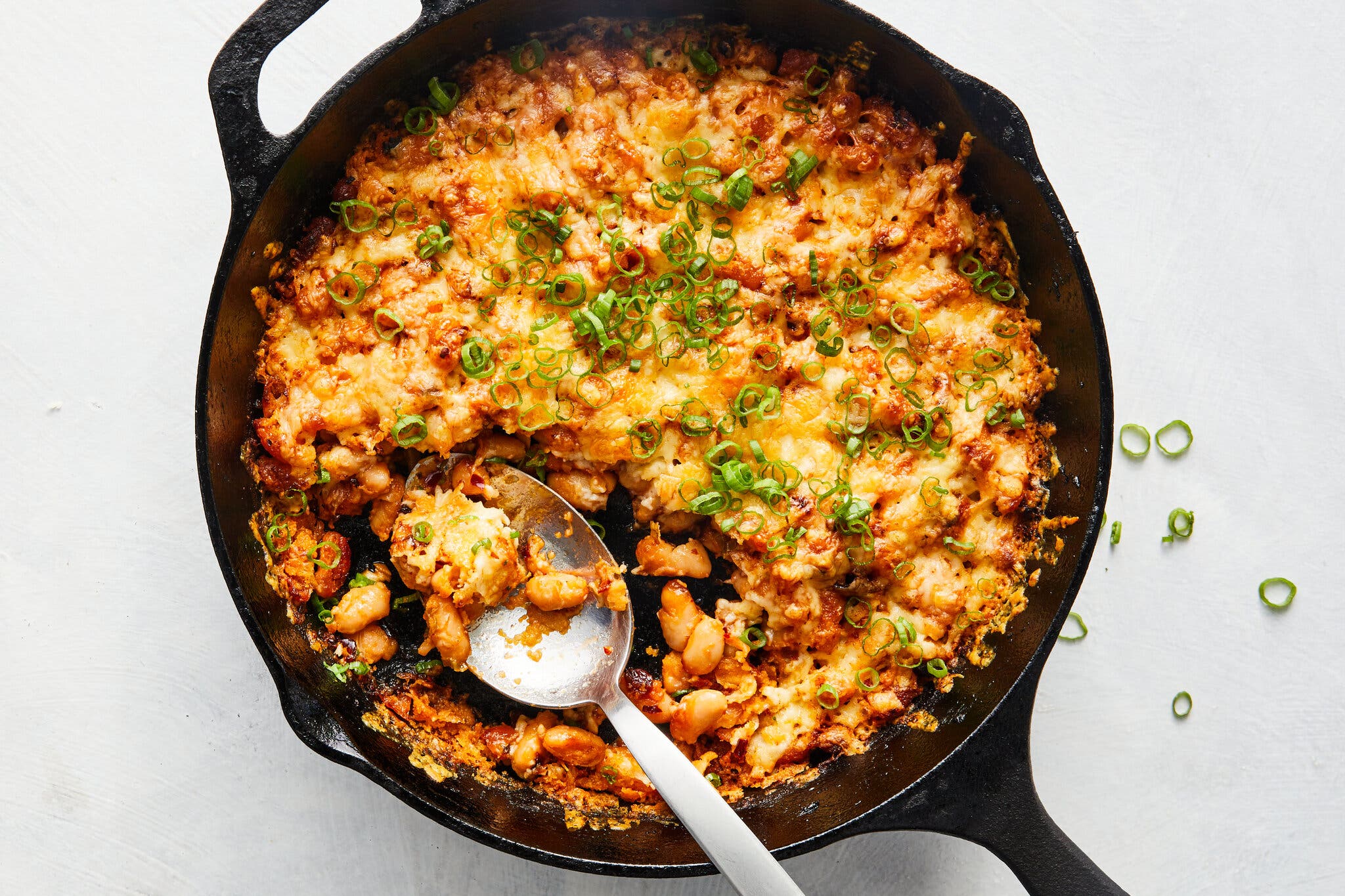 An overhead image of a cast iron skillet with cheesy chile crisp white beans.