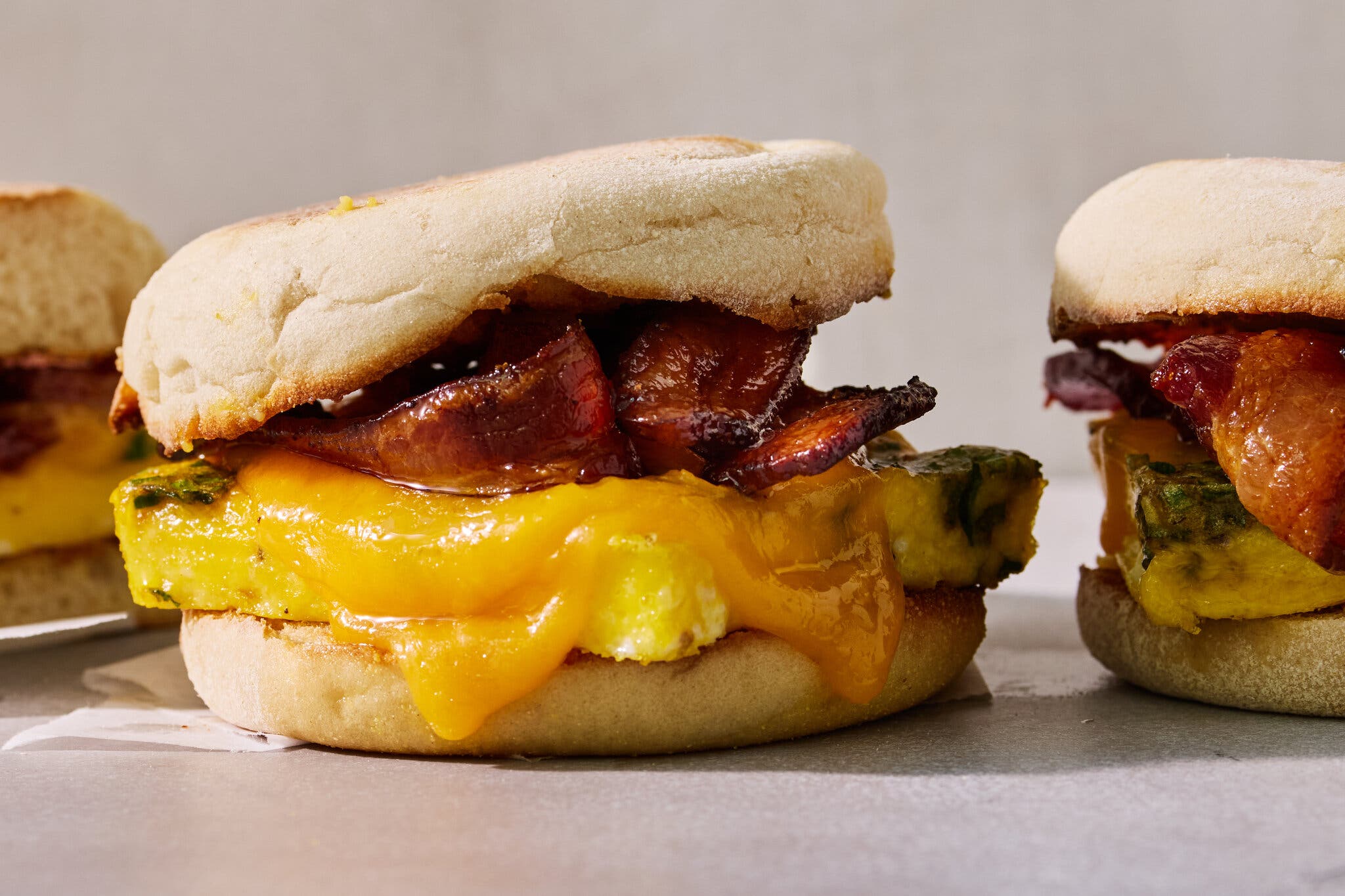 A side image of an English muffin filled with bacon, eggs and cheese.