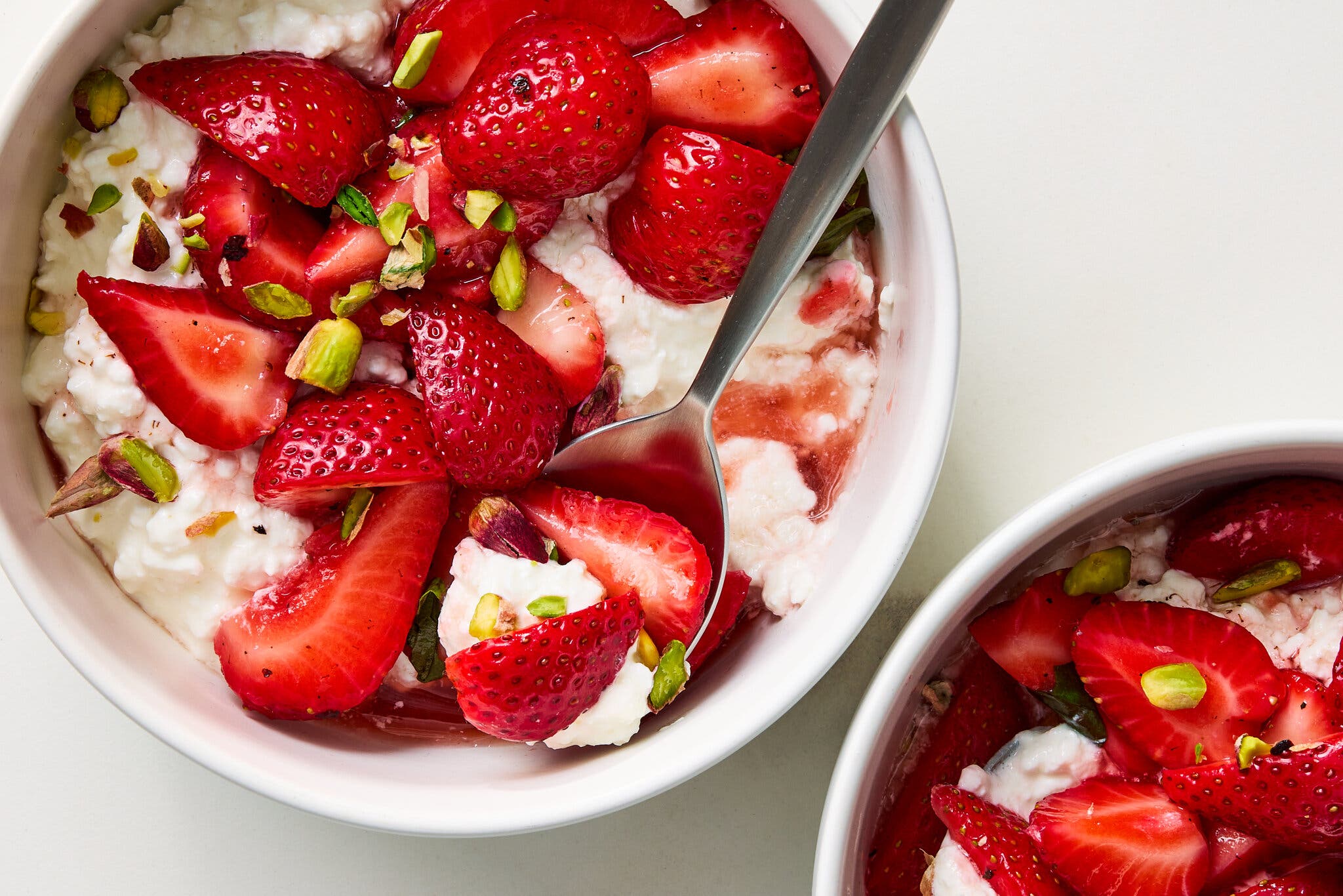 An overhead image of two bowls filled with cottage cheese topped with strawberries.