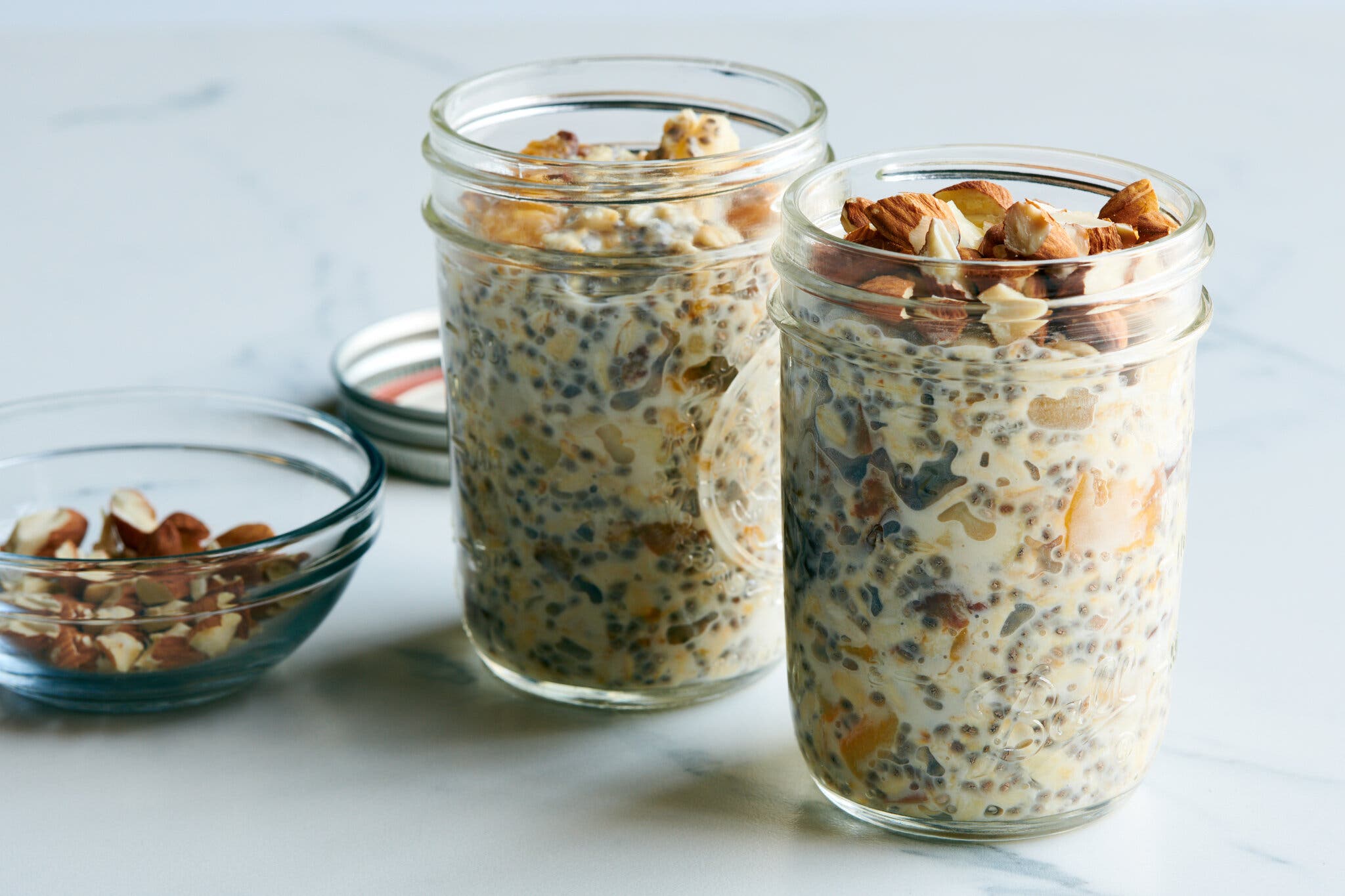 A side image of two jars of overnight oats topped with nuts.