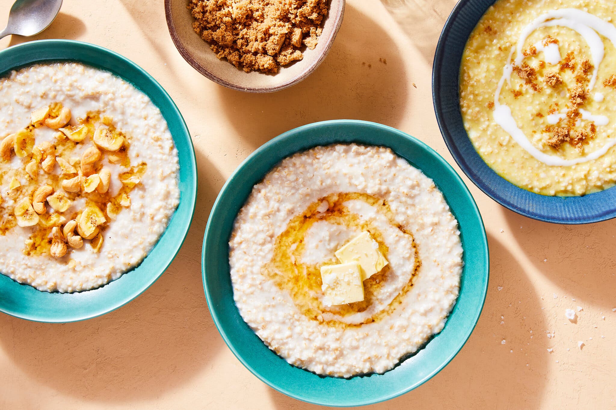 Three bowls of cooked oats are photographed from above.