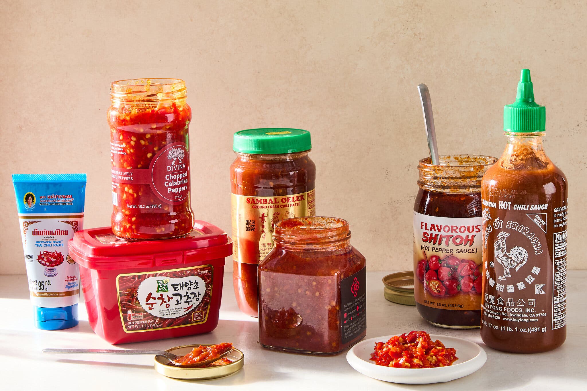 Tubes, jars and containers of red chile pastes sit on a counter.