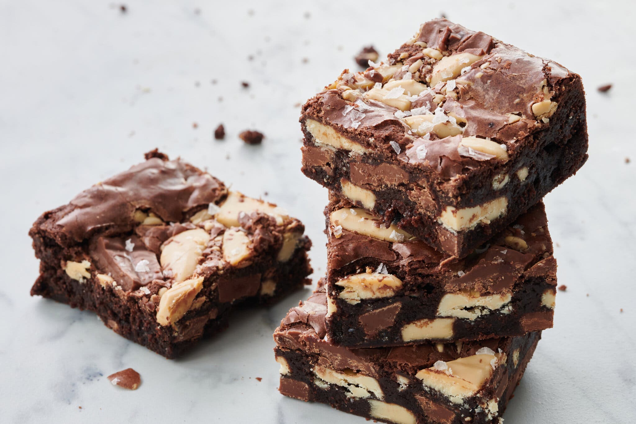A stack of three terrazzo-esque triple-chocolate brownies. To the left of the stack sits a single brownie square.