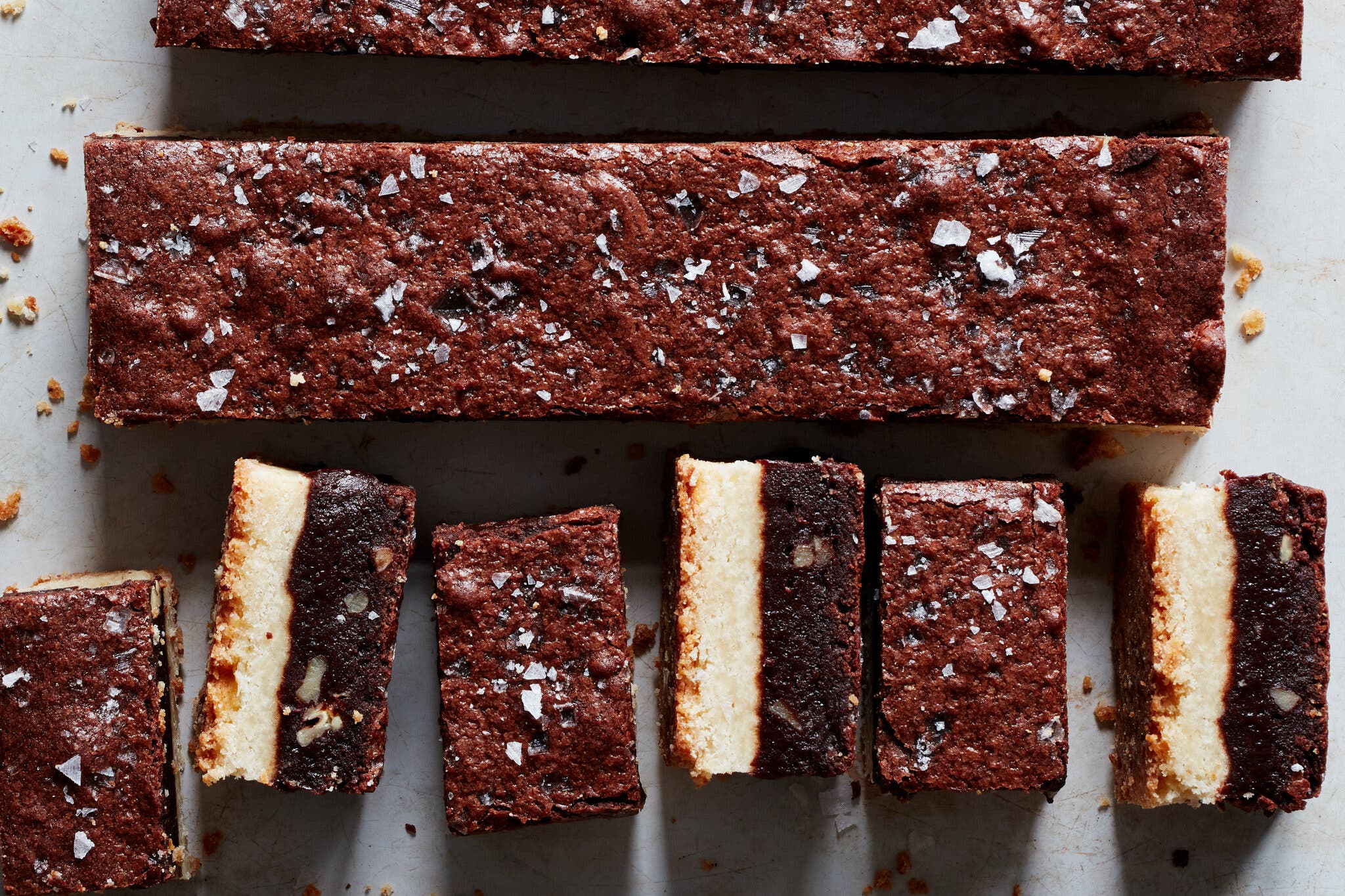 An overhead image of brownie shortbread. For the top two rows, you can see only the brownie topping. The bottom row is cut into smaller bars, and turned on their sides to show the shortbread base.