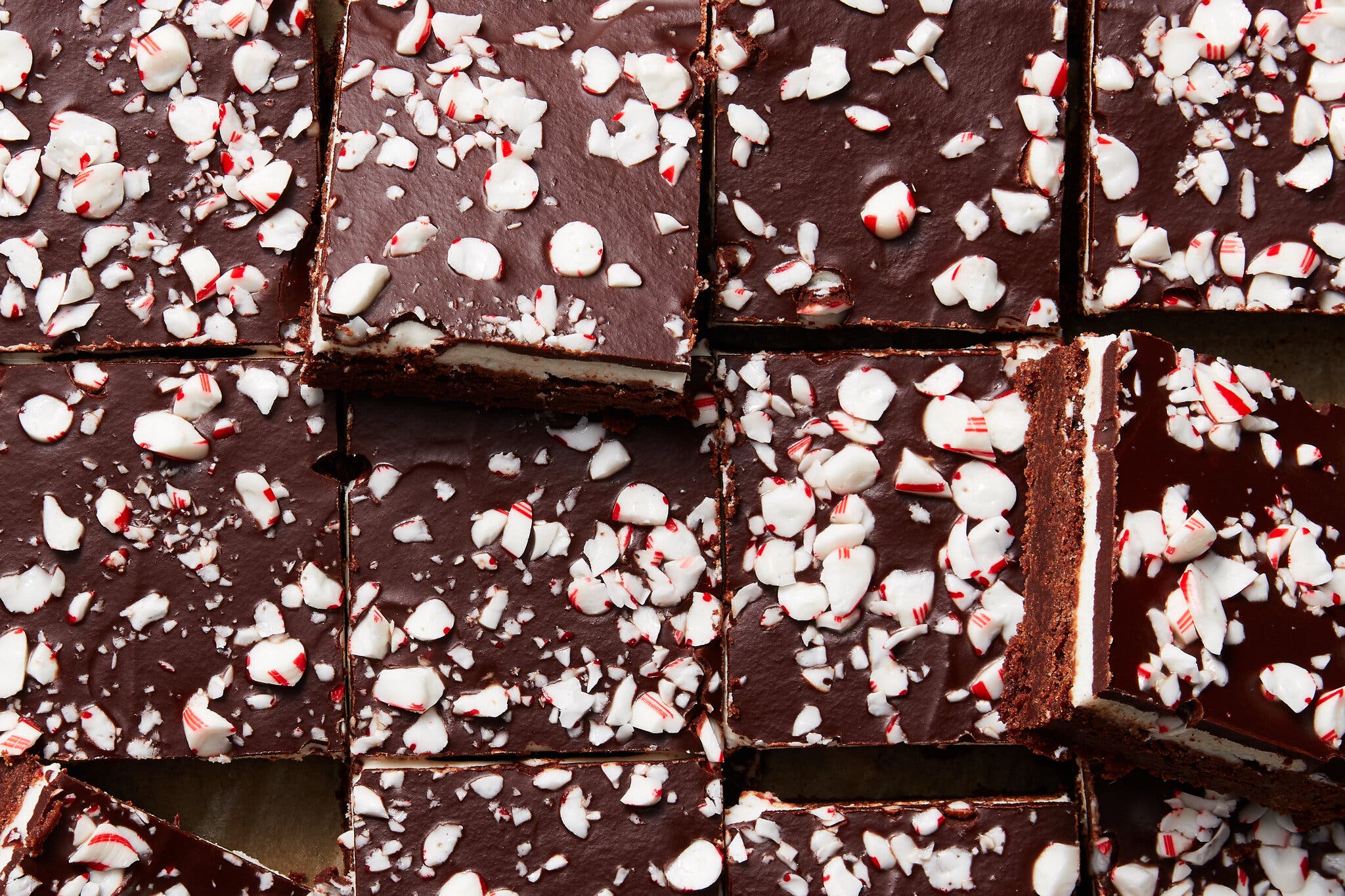 An overhead image of brownies with white, peppermint filling topped with a layer of chocolate ganache and crushed peppermints.