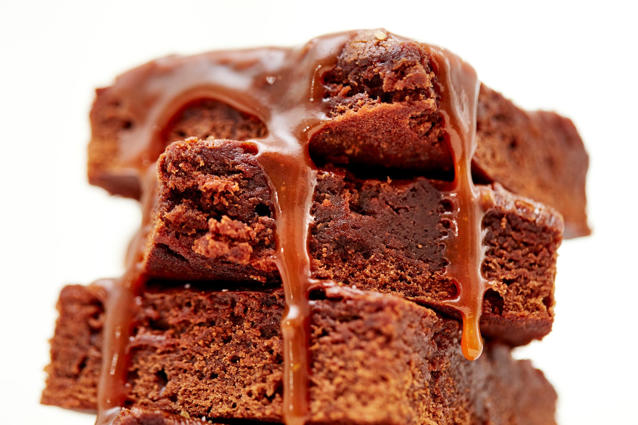 A stack of three salted caramel brownies with caramel drizzled on top.