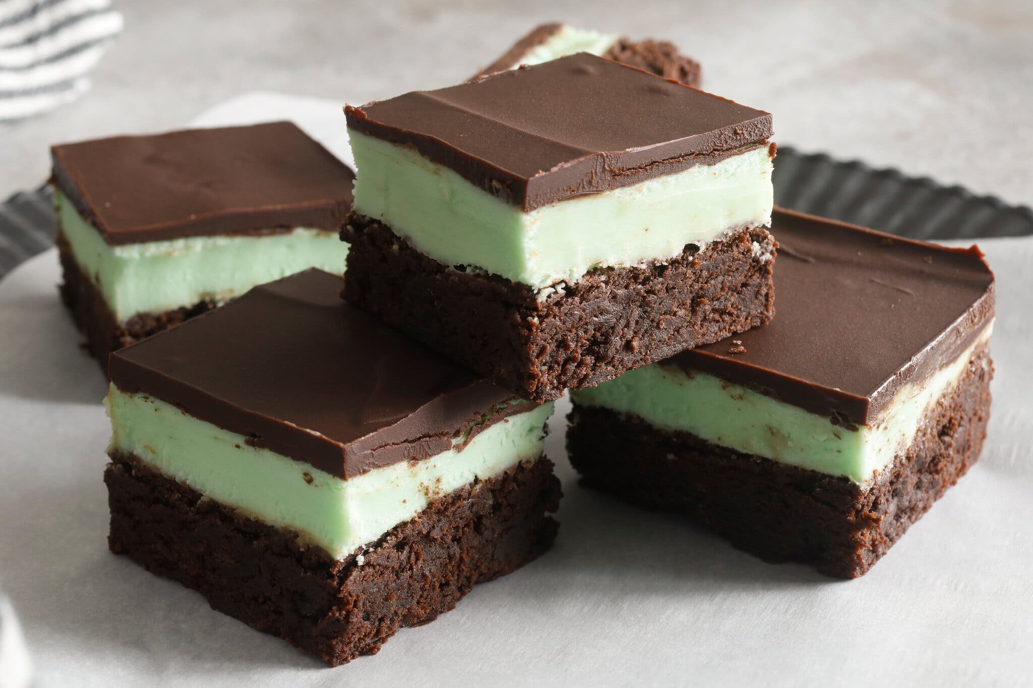 A small pyramid of grasshopper brownies, with a brownie base, a light green crème de menthe center and a chocolate ganache top.