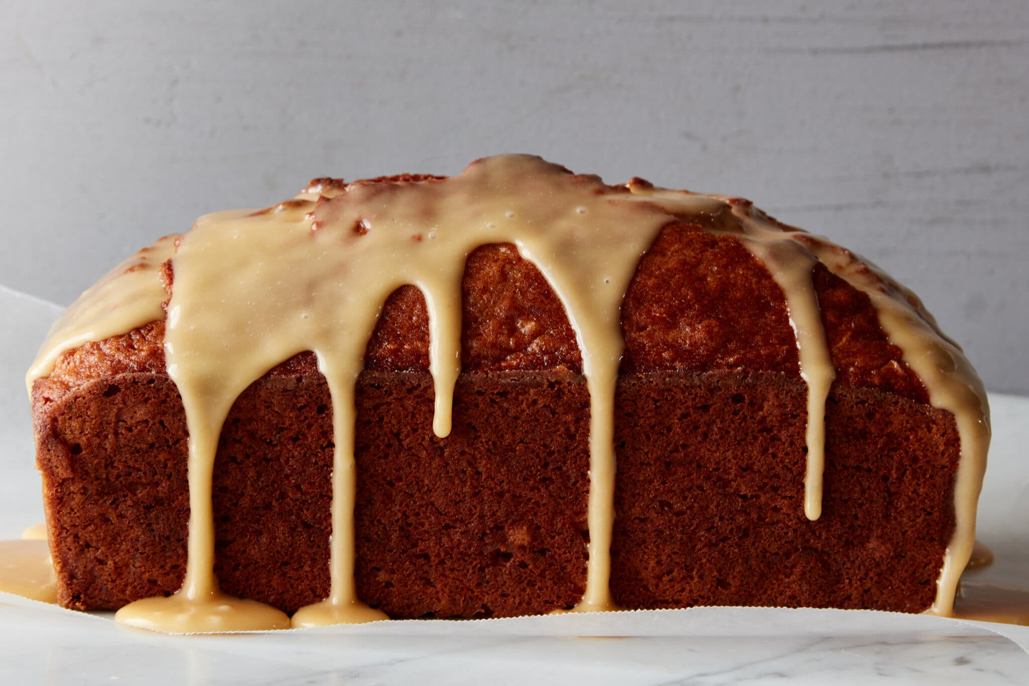 A side image of a loaf cake coated in a tan icing.