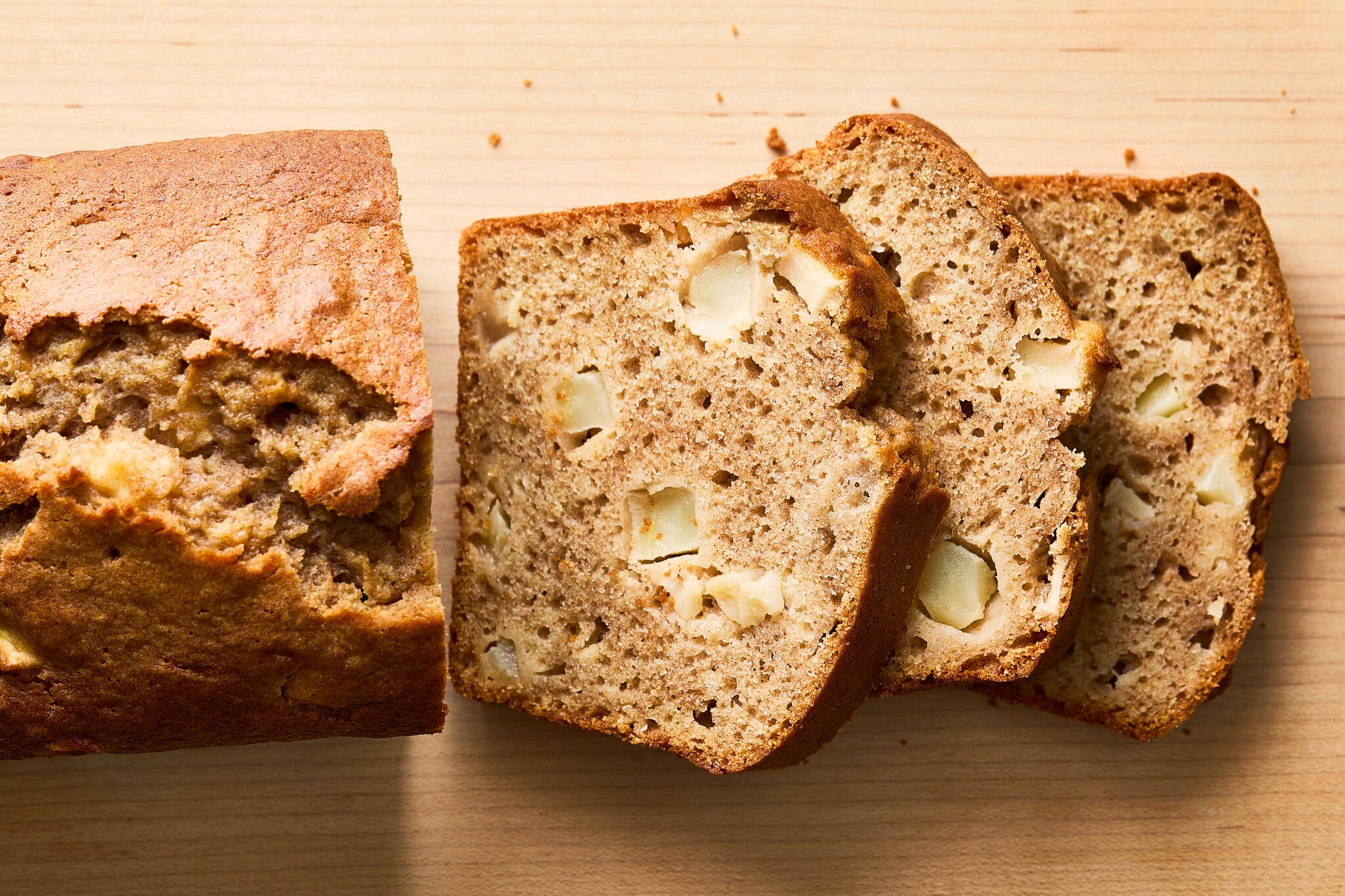 An overhead image of a loaf sliced and studded with apple chunks.