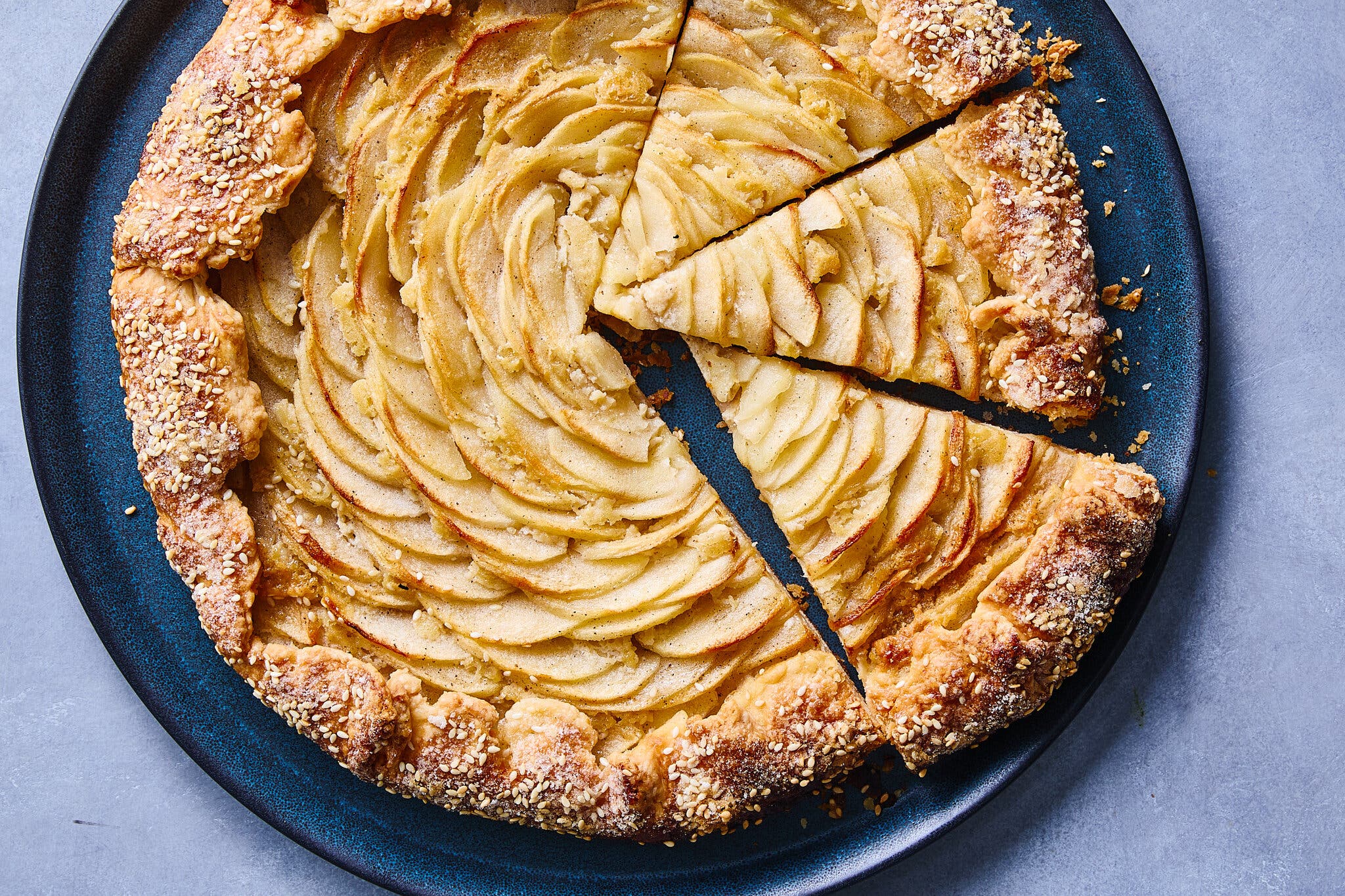 An overhead image of an open-face apple tart with a sesame-topped crust.
