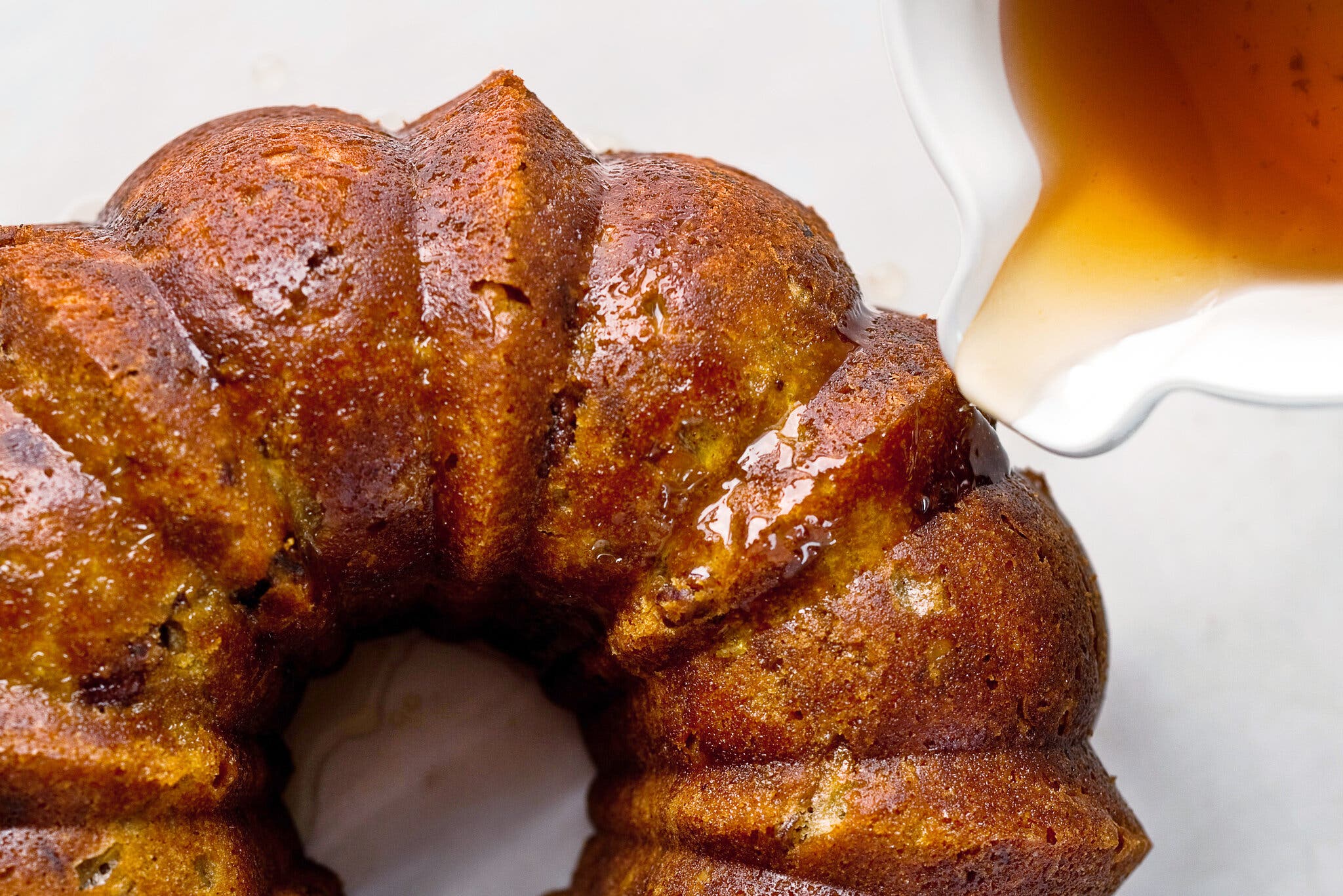 An overhead image of a bundt cake being drizzled with a bourbon soak.
