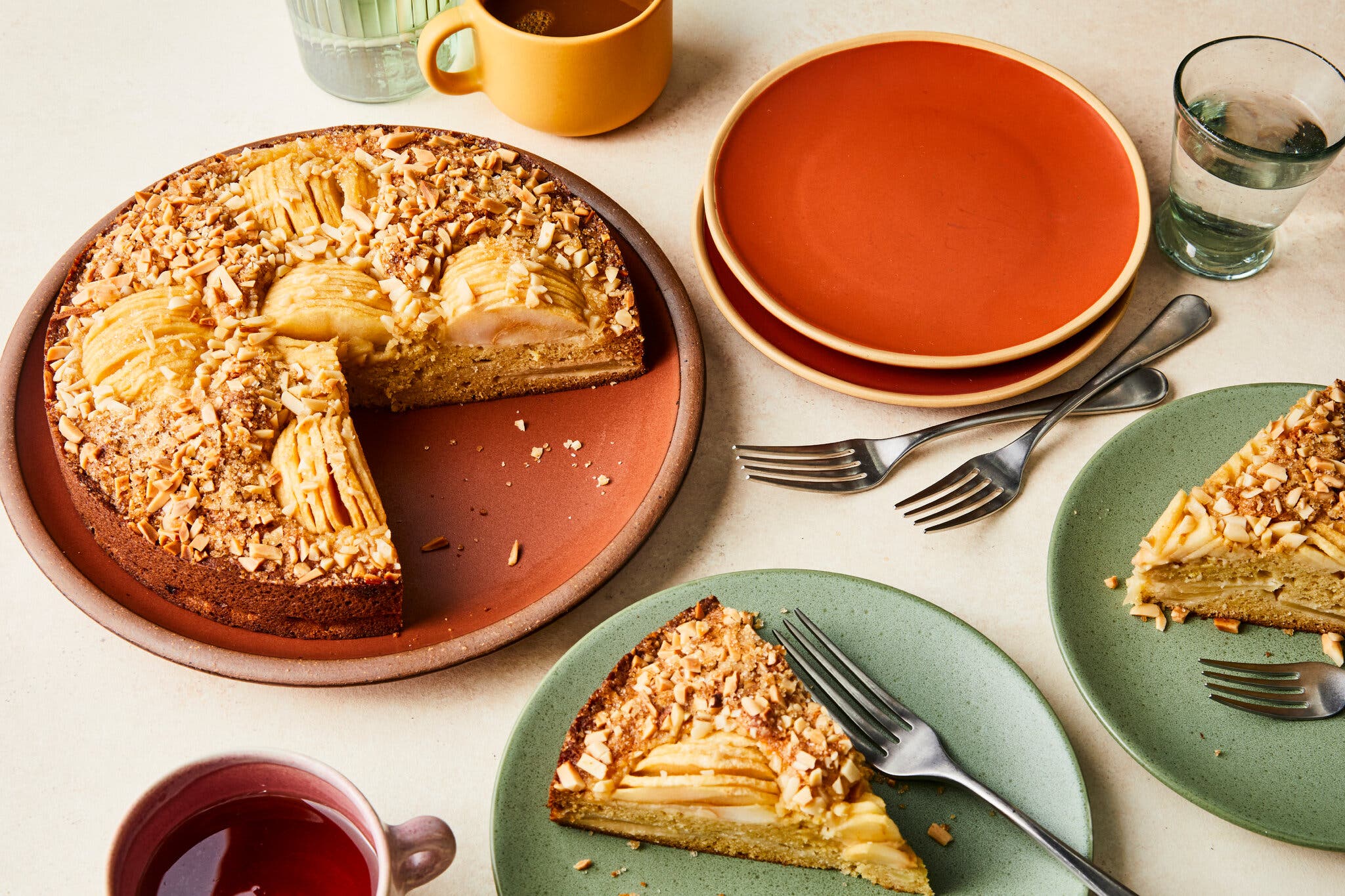An angled image of an apple cake on a platter with two slices taken out.