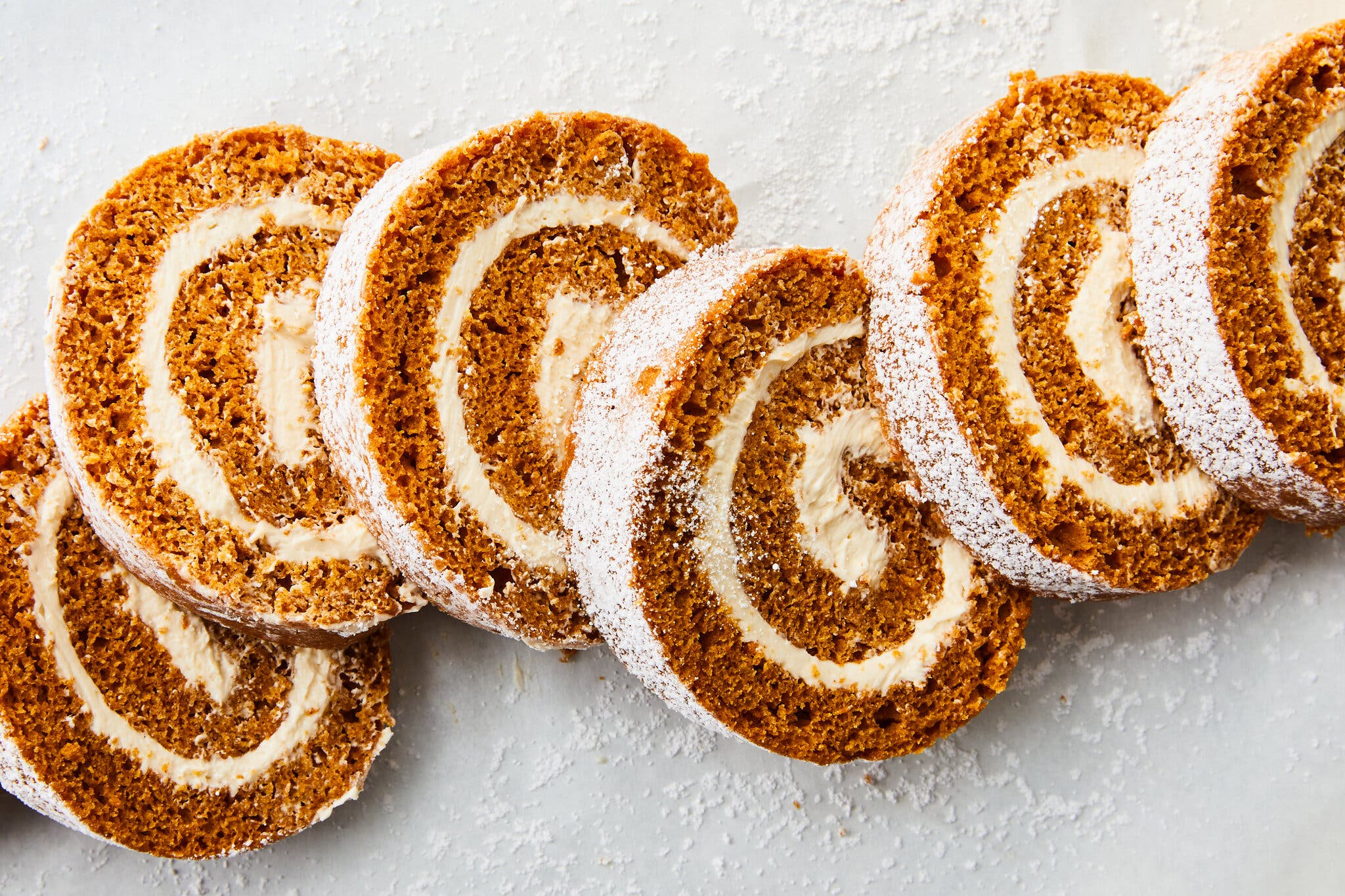 An overhead image of a sliced pumpkin roll dusted with powdered sugar.