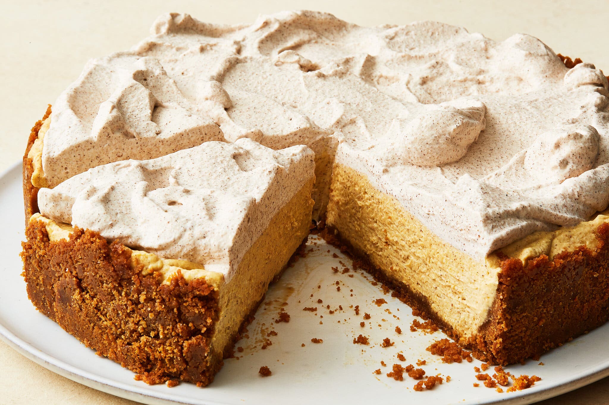 A side shot of no-bake pumpkin cheesecake with a cookie crust and cinnamon whipped cream.