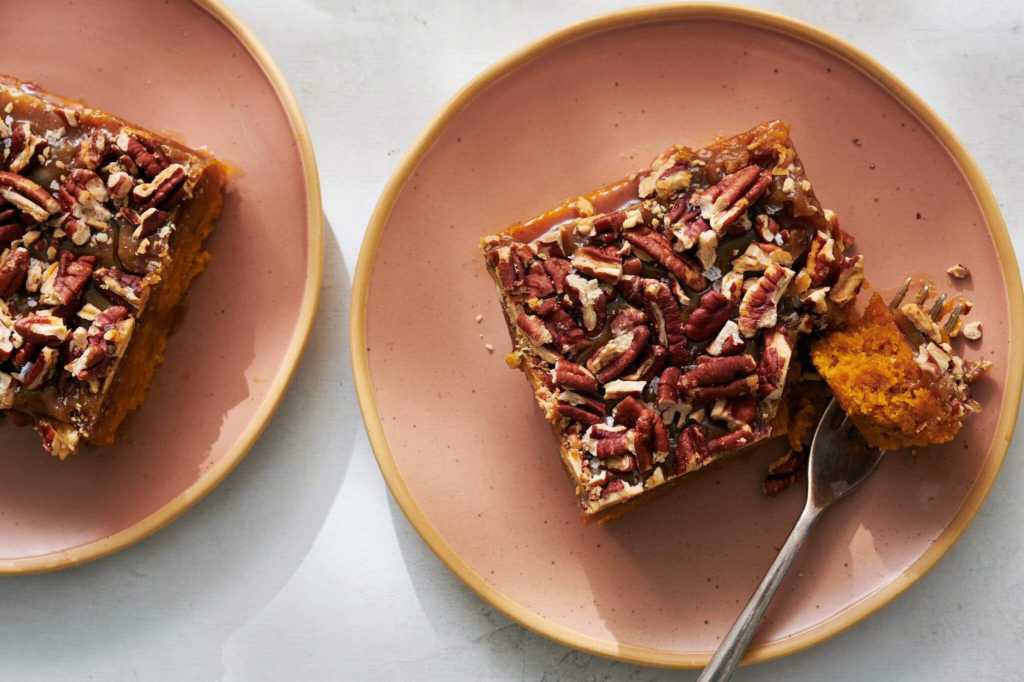 An overhead image of a pair of plates with square slices of pumpkin pecan sheet cake.