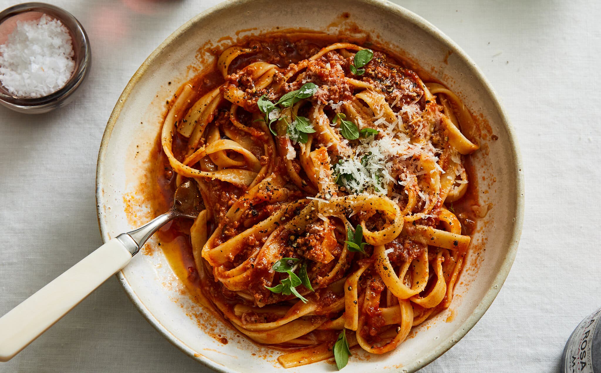 An overhead image of a bowl of quick lamb ragù. To the top left is a small pinch bowl of flaky salt.