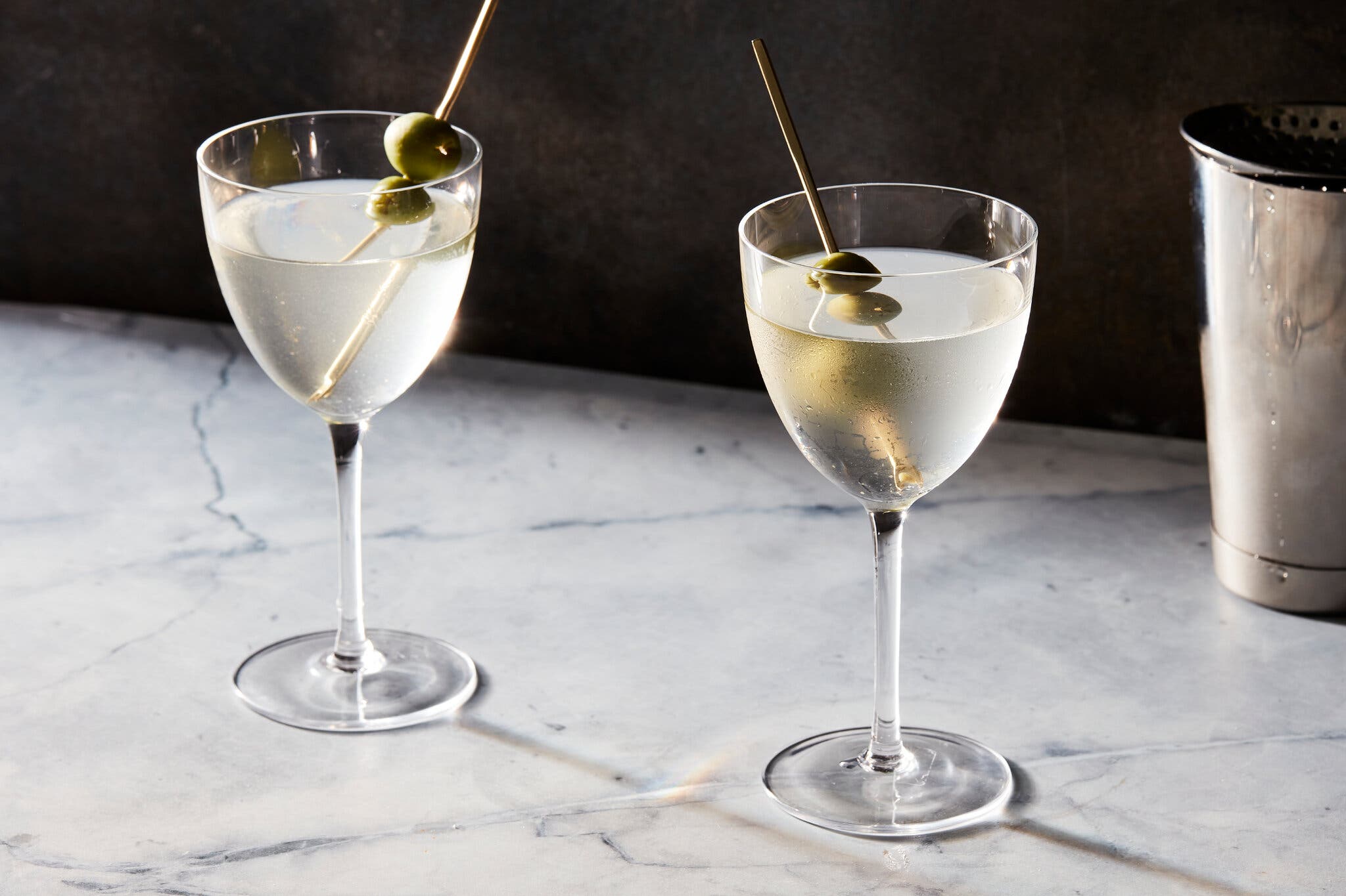 A side image of two dirty martinis with olive garnish.
