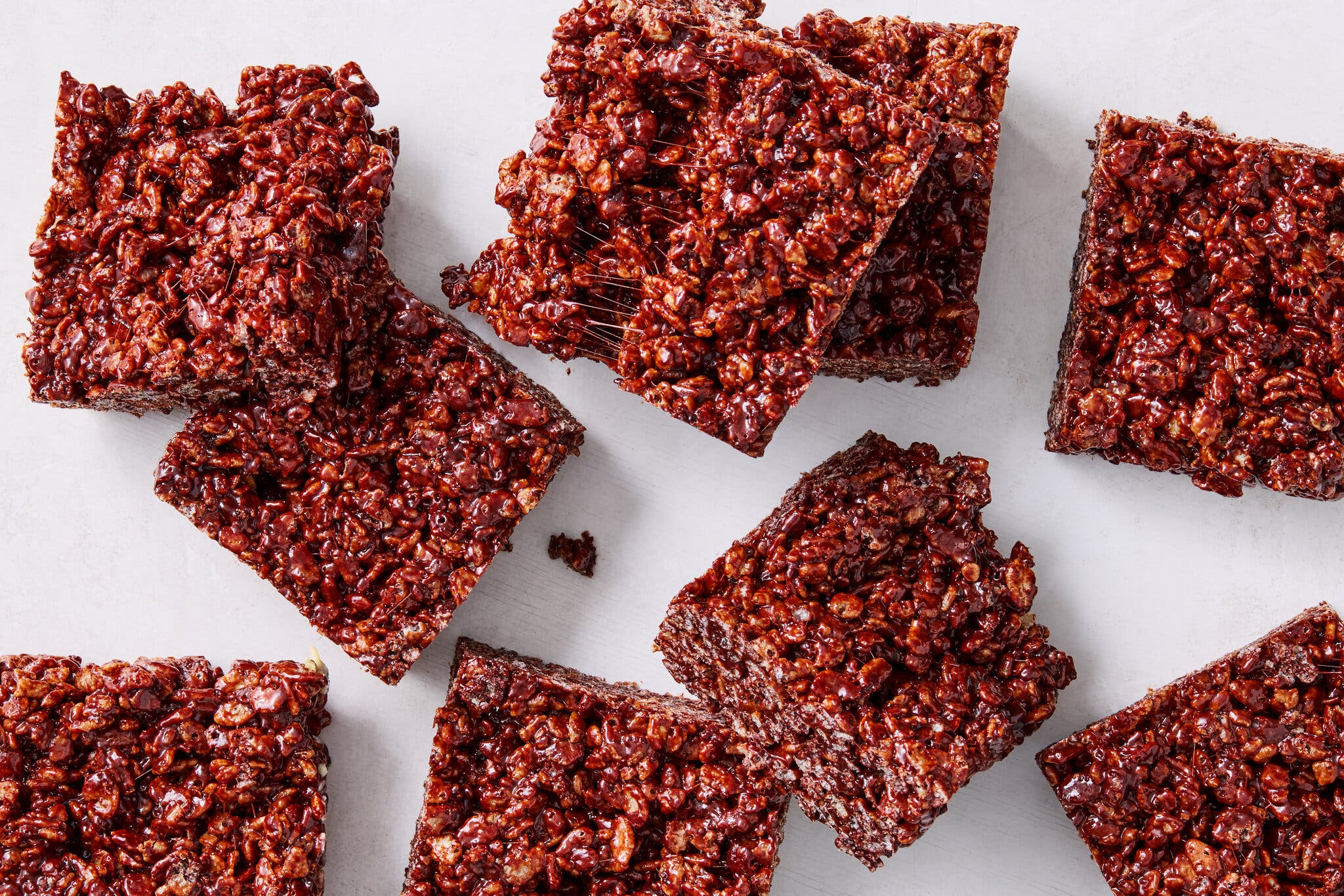A close-up, overhead view of several chocolate Rice Krispies treats arranged on a white background.