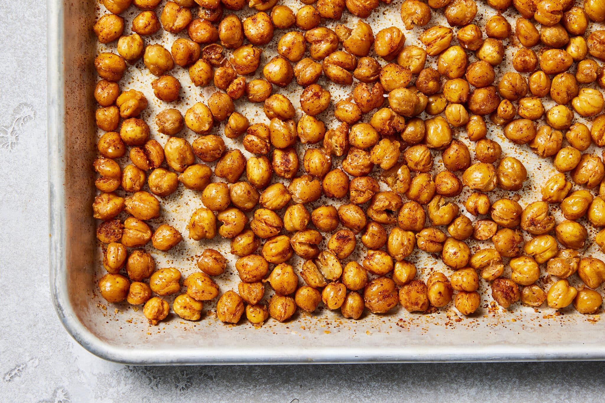 An overhead image of roasted chickpeas on a sheet pan.
