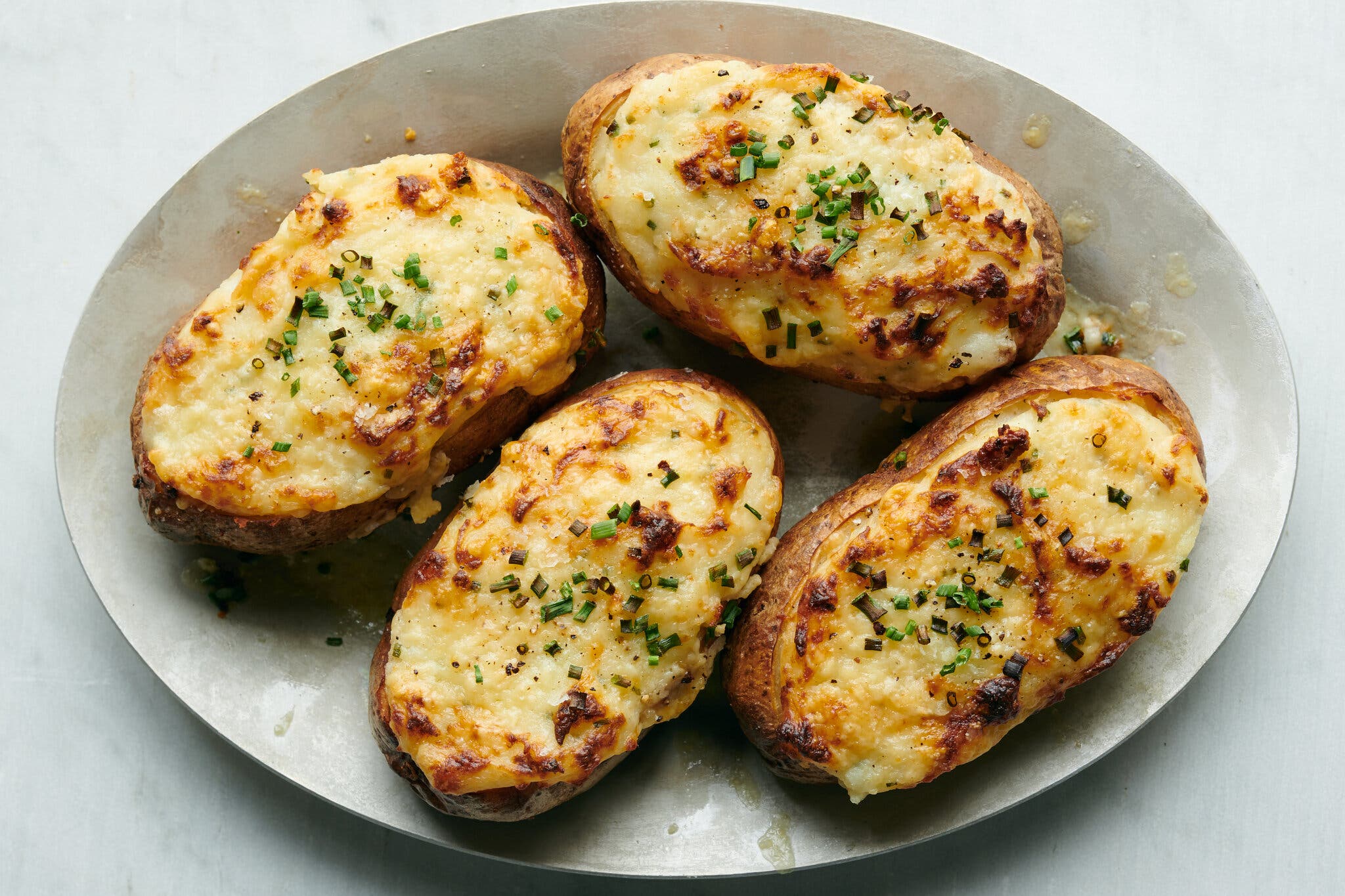 An overhead image of four twice-baked potatoes topped with chives.