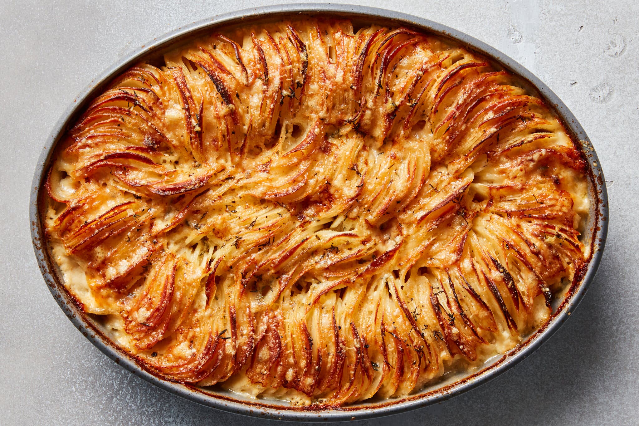 An overhead shot of cheesy Hasselback potato gratin showing ruffled potatoes coated in browned, melted cheese.
