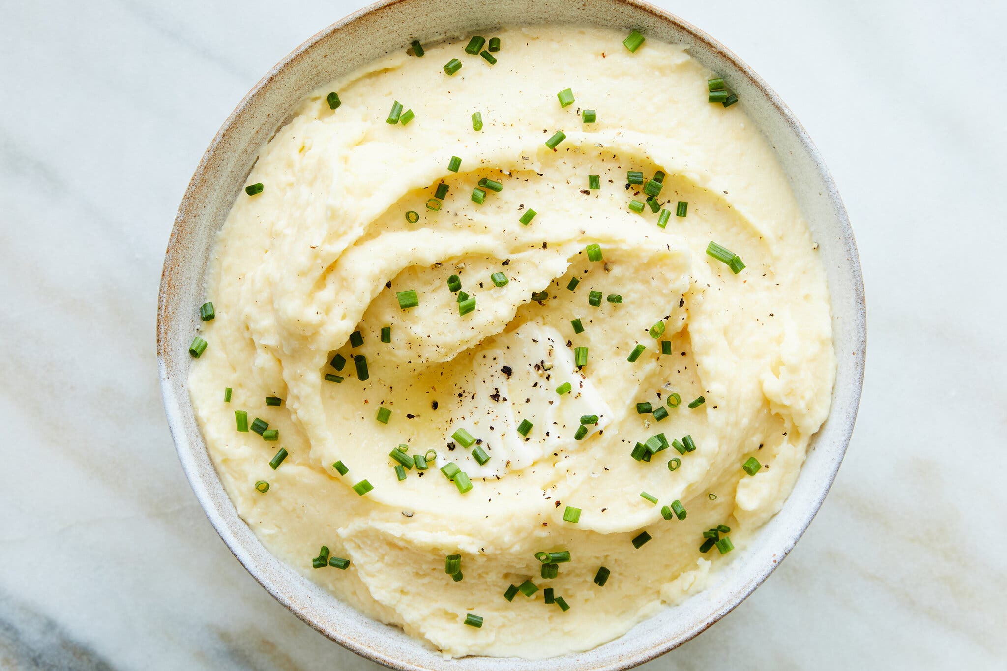 A small bowl of mashed potatoes finished with chives shot from overhead.