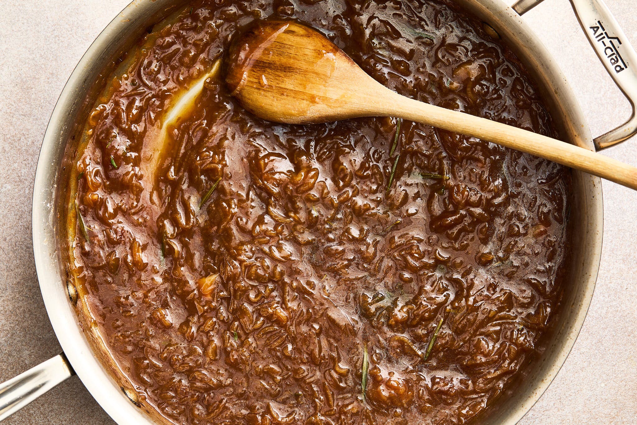 An overhead shot of a pan of caramelized shallot gravy. A spatula sits on top of the pan.