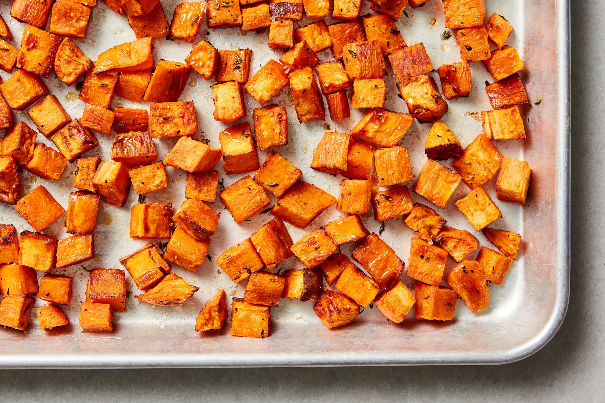 An overhead shot of a sheet pan of roasted sweet potatoes.