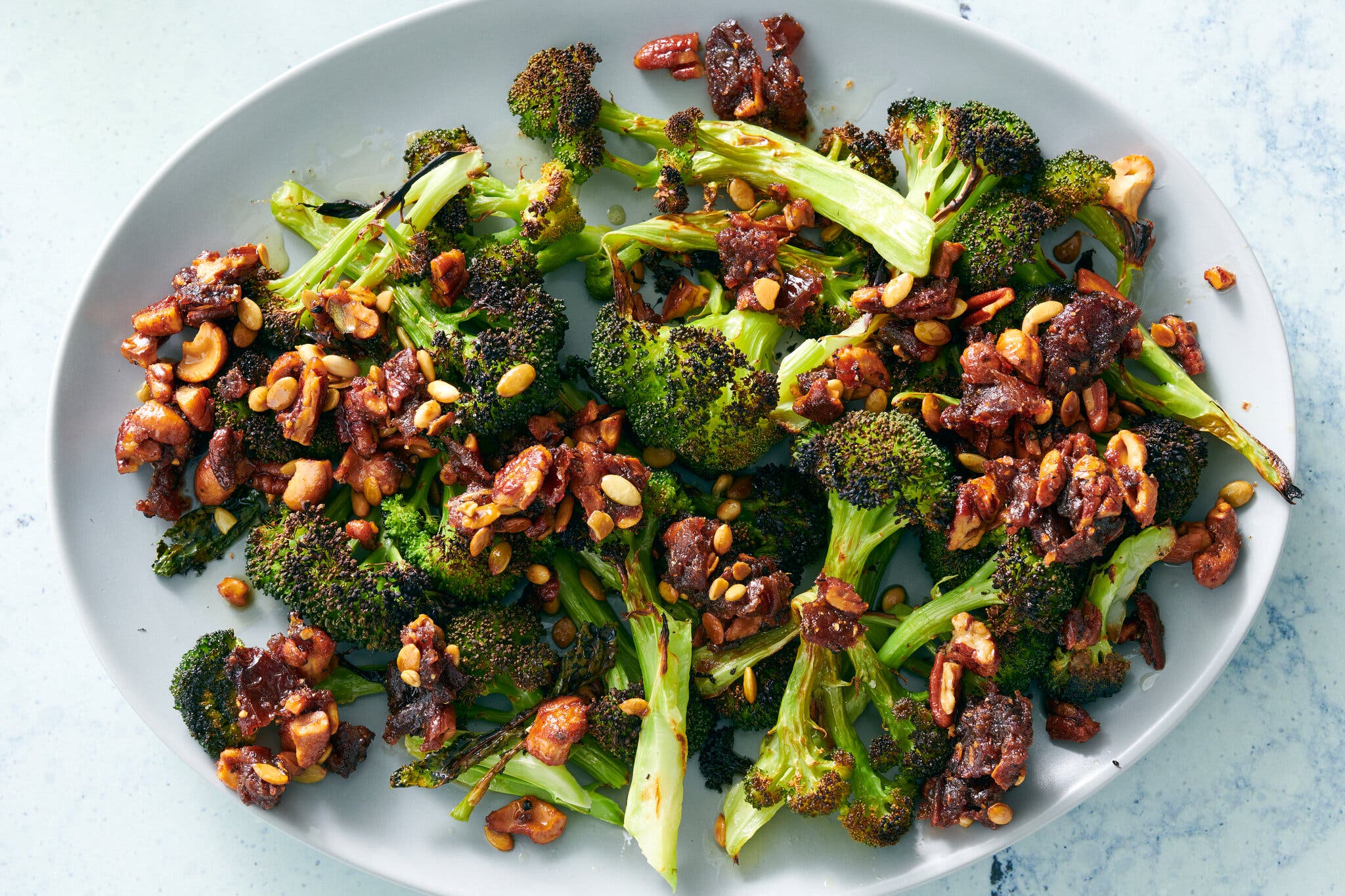 An overhead shot of a white plate of broccoli with sizzled nuts and dates. 
