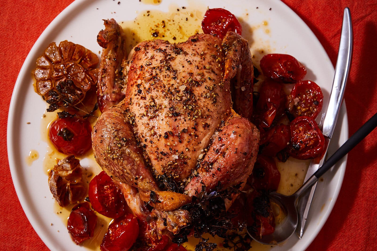 An overhead image of a roast chicken surrounded with tomatoes.
