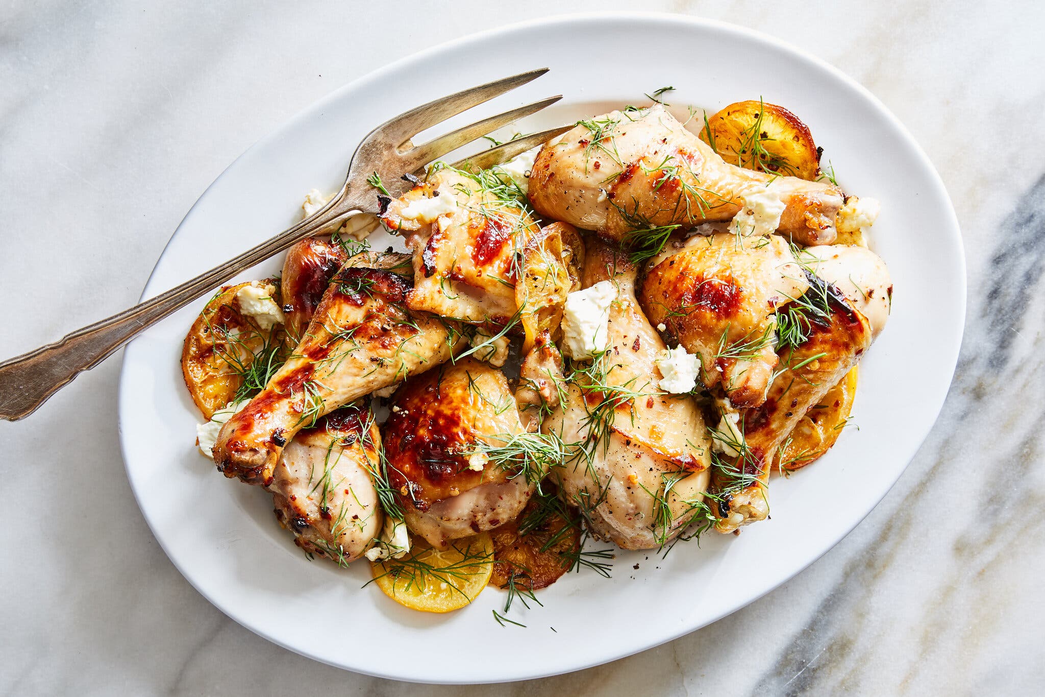 An overhead image of a broken-down roast chicken topped with herbs and cheese.