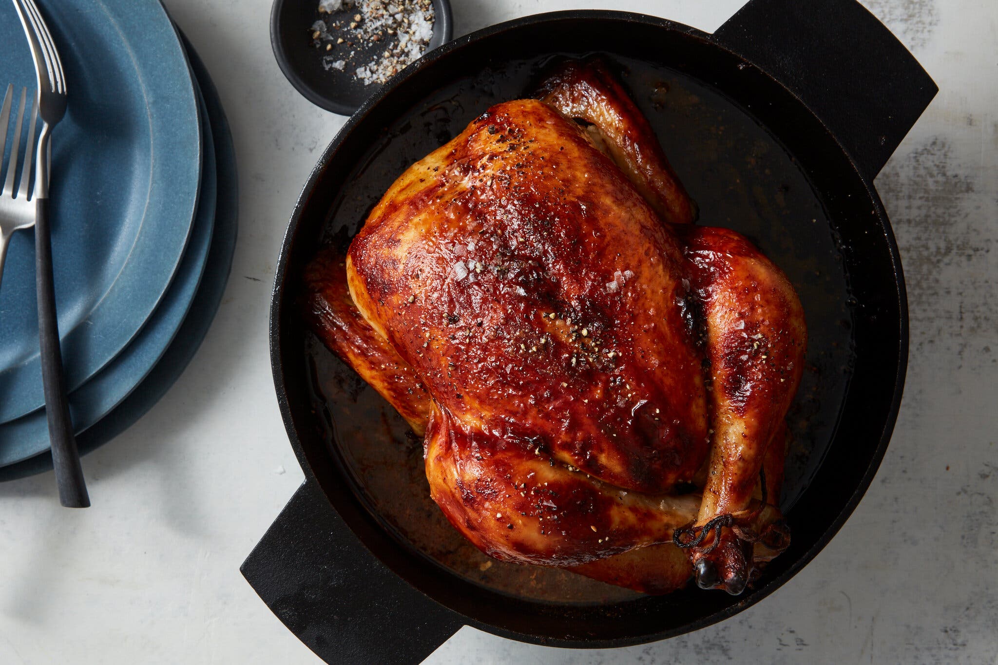 An overhead image of a burnished roast chicken in a cast-iron skillet.