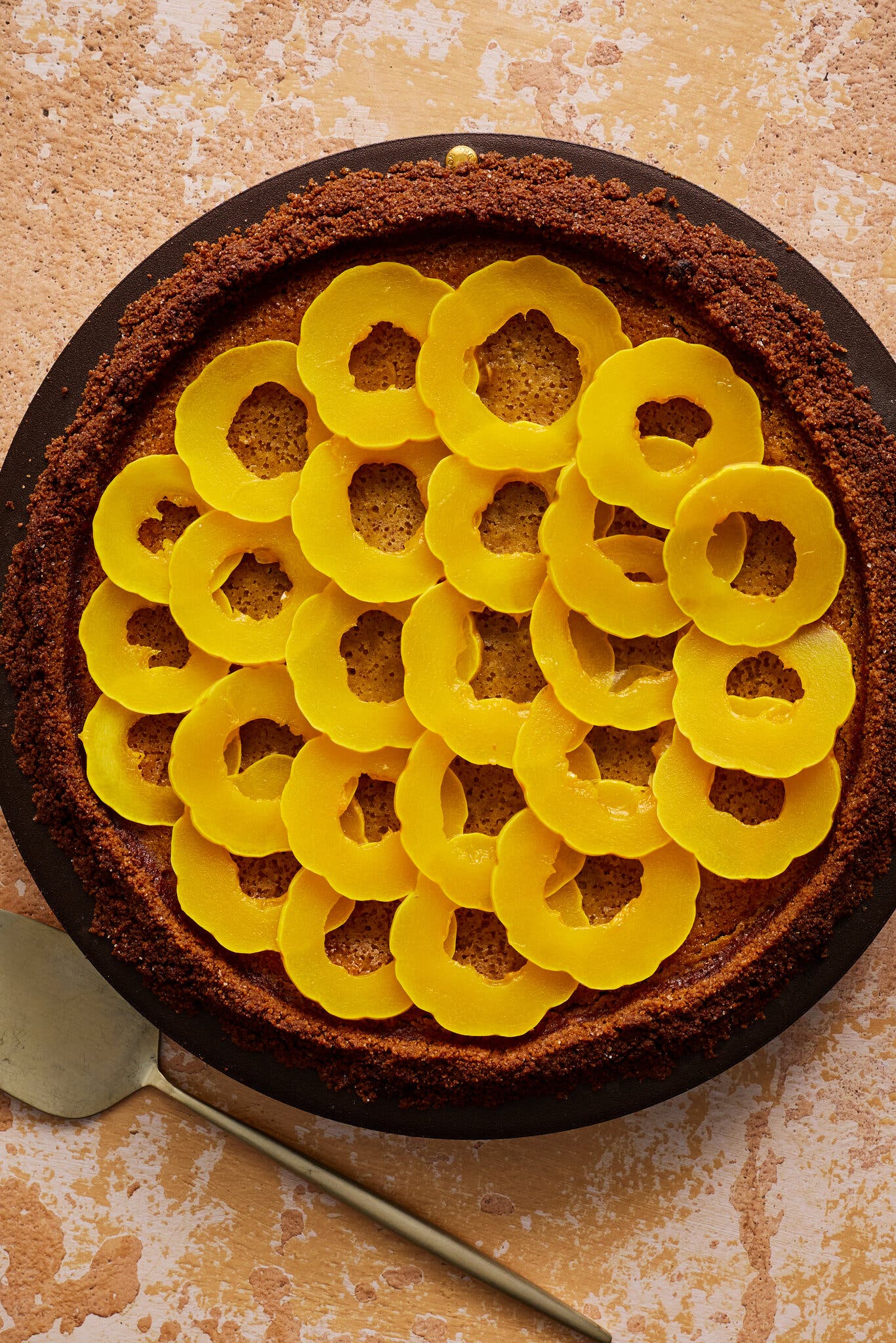 An overhead shot of a pie with a crumbly brown crust, topped with layered rings of delicata squash.