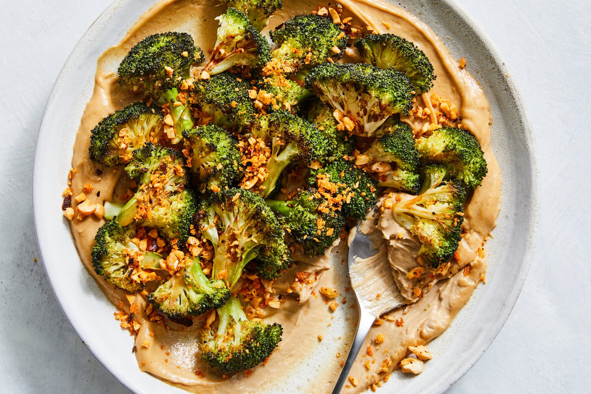 An overhead image of roasted broccoli on a bed of whipped tofu and cashew butter.