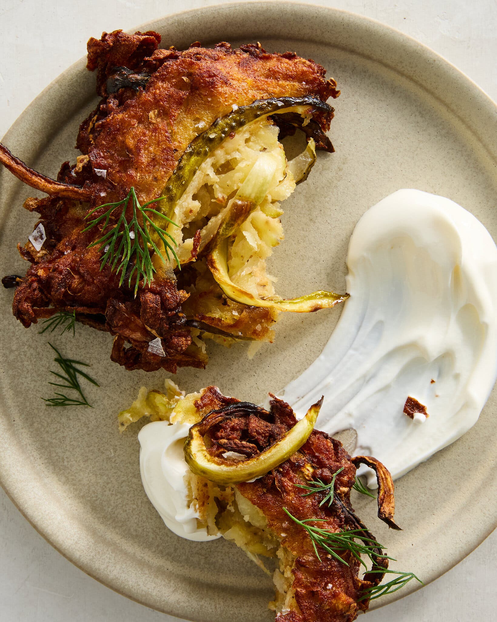 A latke is broken open and swiped through sour cream.