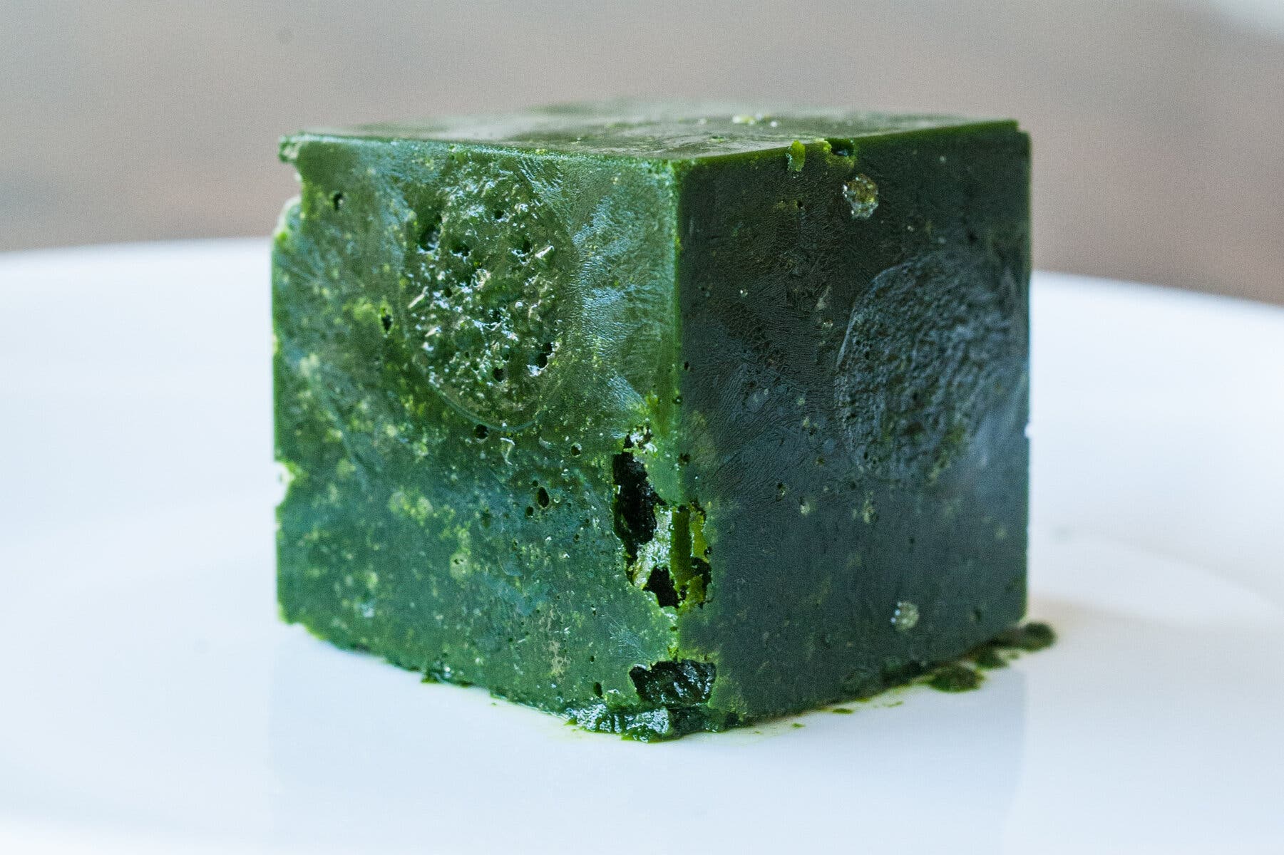 A side image of a green cube on a plate.