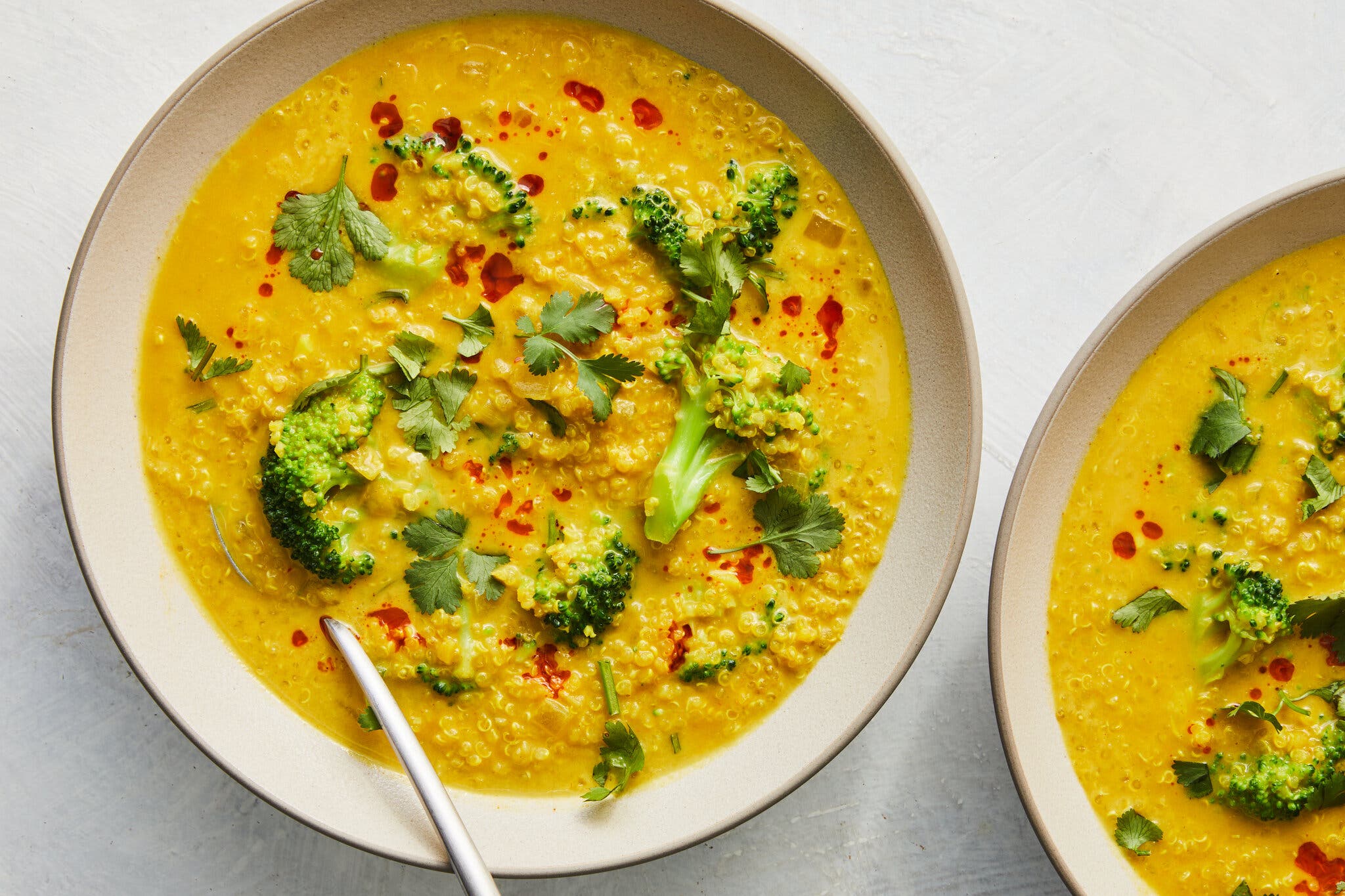 An overhead image of a bright orange soup topped with broccoli.